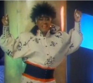 Screen grab of Patti Labelle (Black Woman) wearing white outfit with black symbols dancing