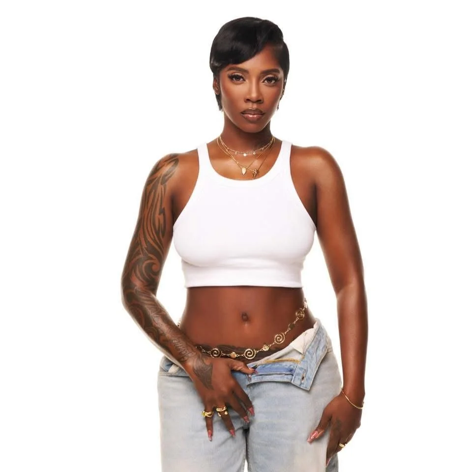 A woman with short black hair, wearing a white crop top and light blue jeans, standing against a white background.