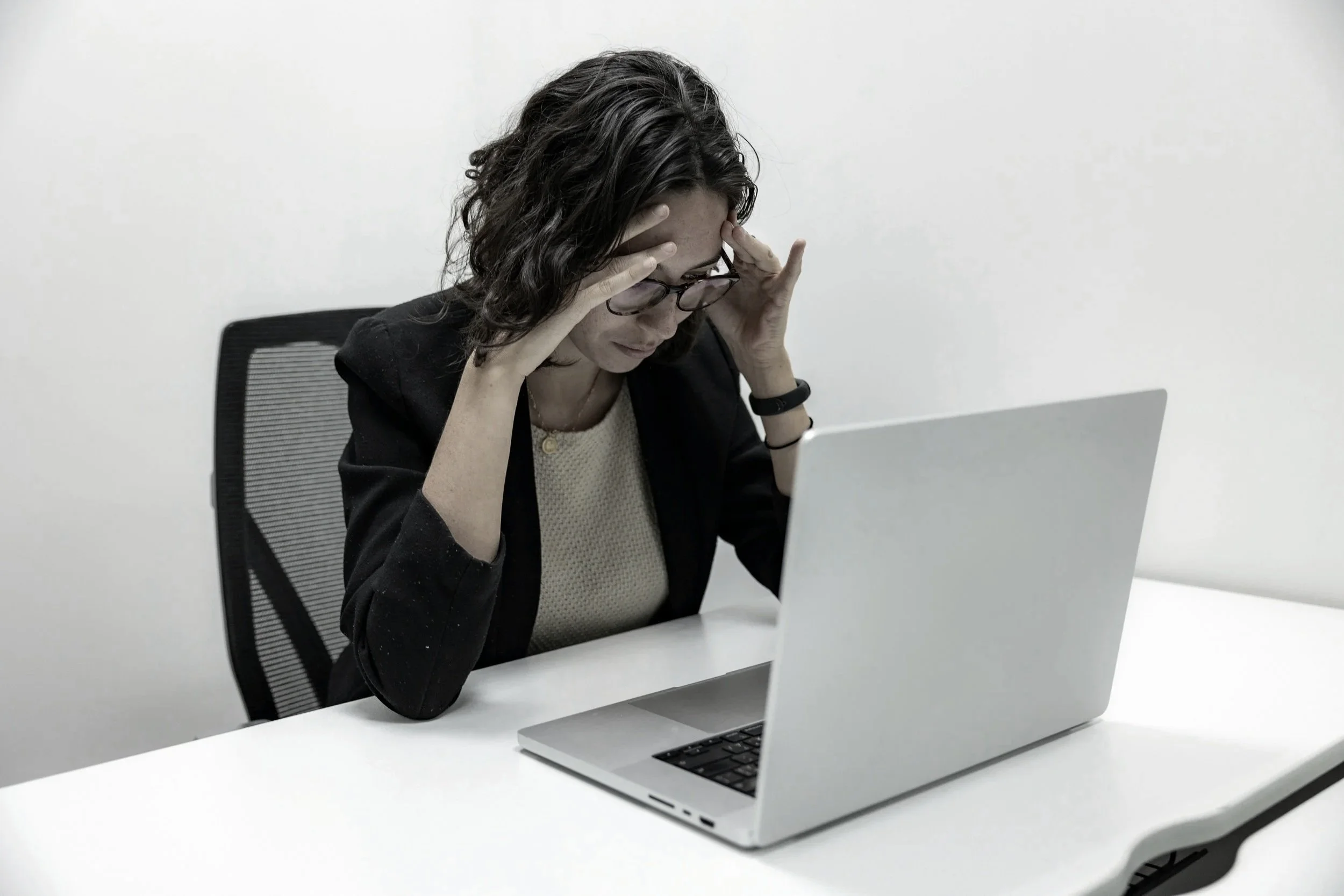 Desk worker feeling stressed, mentally drained, and fatigued while working at a laptop in an office