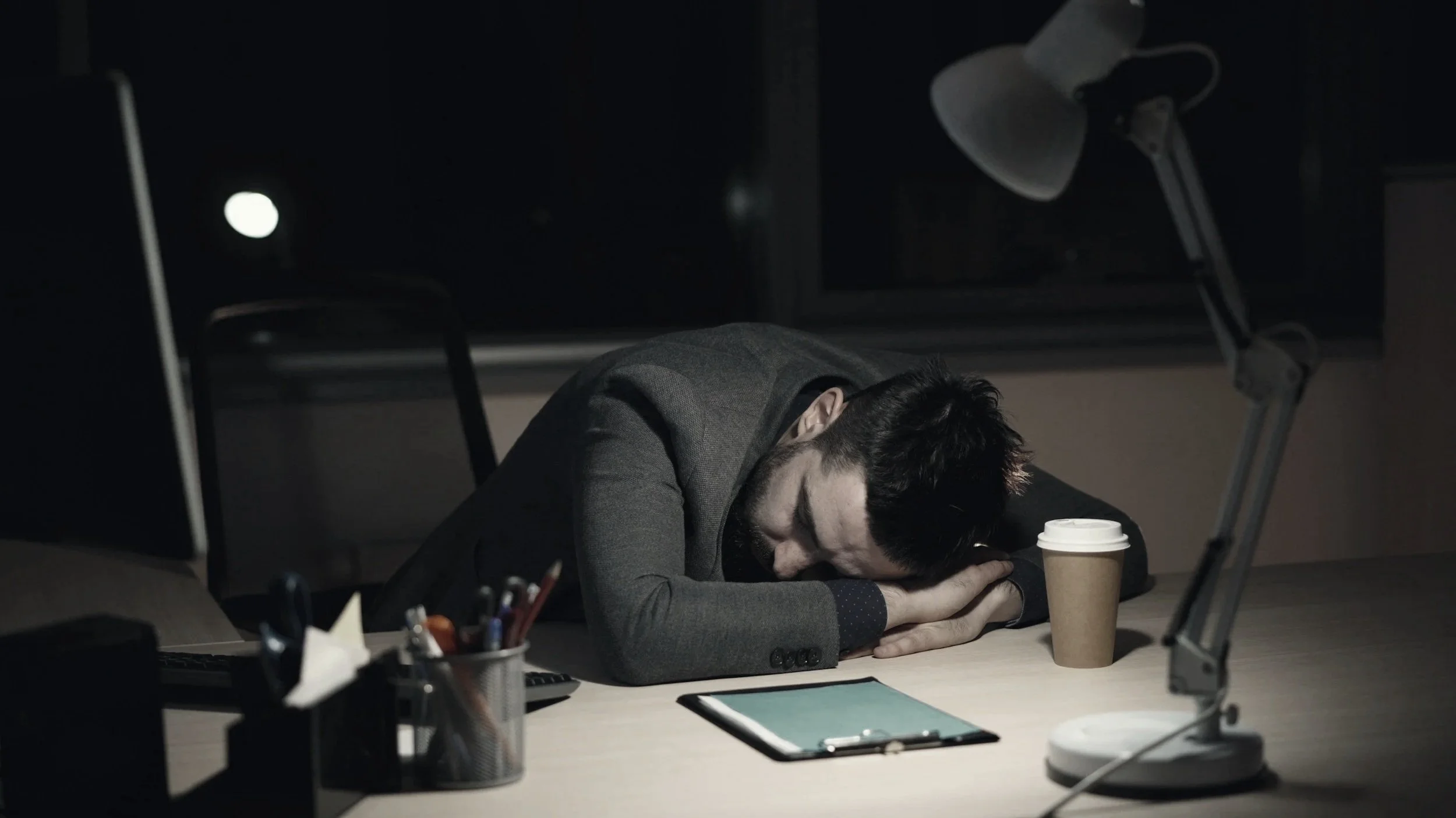 Office worker sleeping at his desk at night from stress, fatigue, and low energy