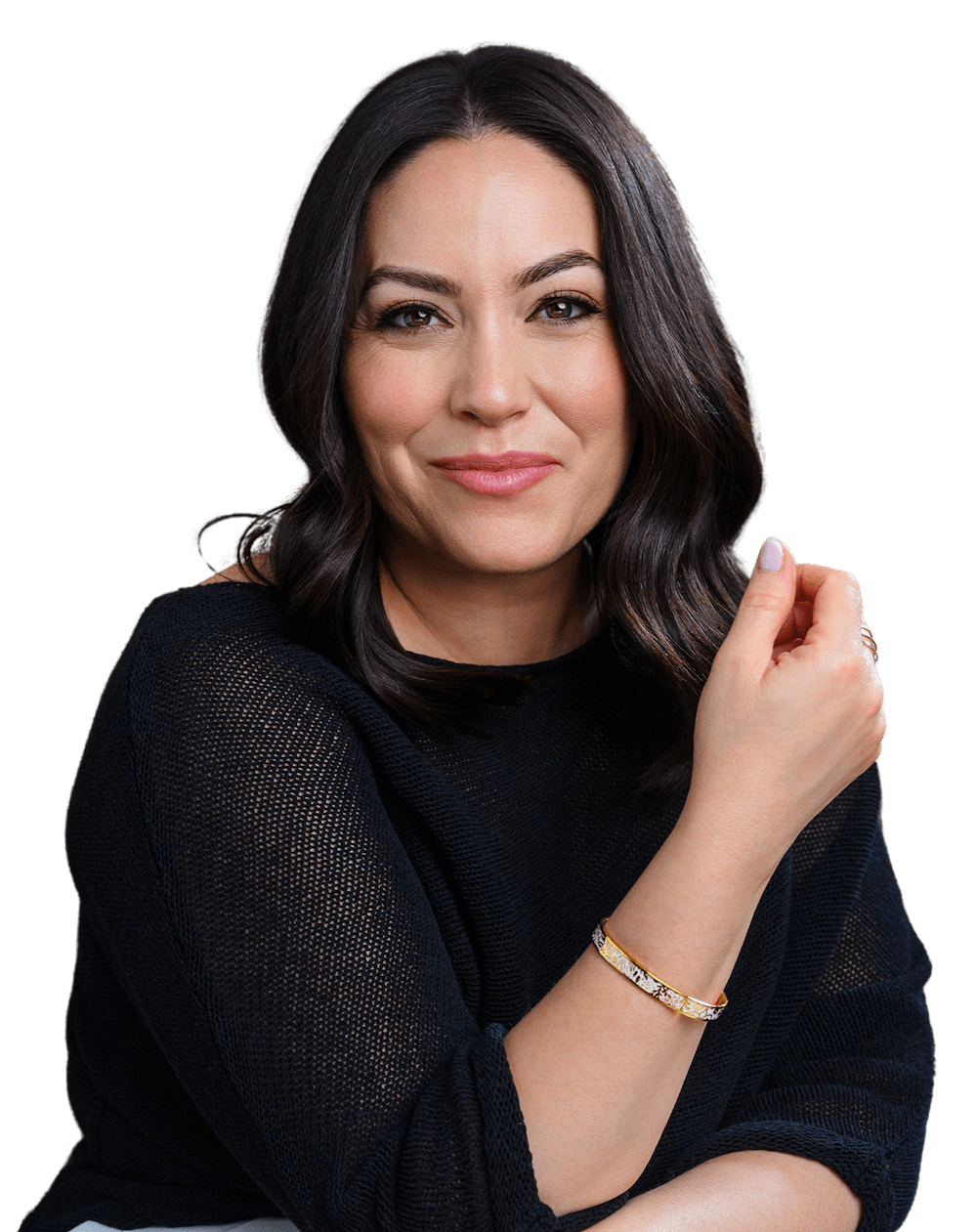 A woman with shoulder-length dark brown hair, wearing a black knit top and a gold bracelet, looking at the camera with a slight smile and her right hand clenched near her face.