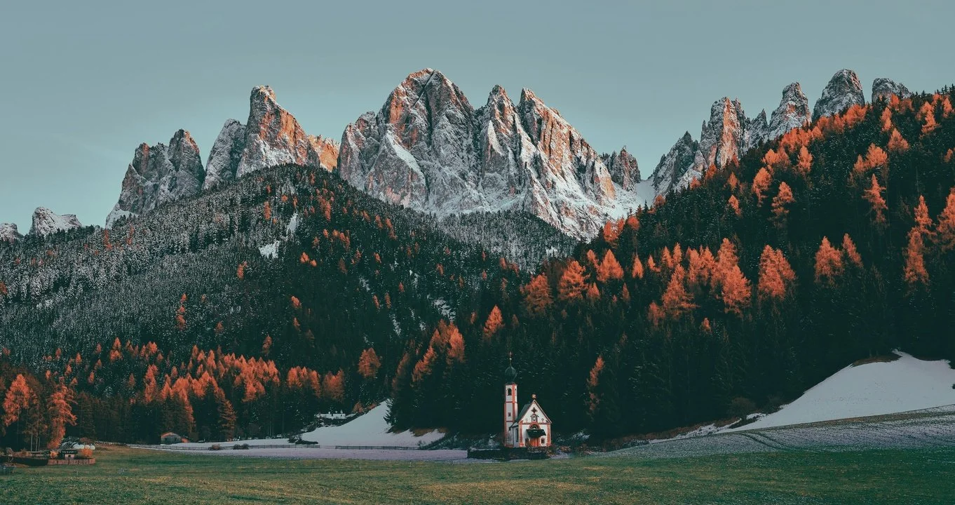 Ranui Chapel (Church of St. John) nestled in the scenic Val di Funes (Funes Valley) with the Odle mountain peaks rising in the background.