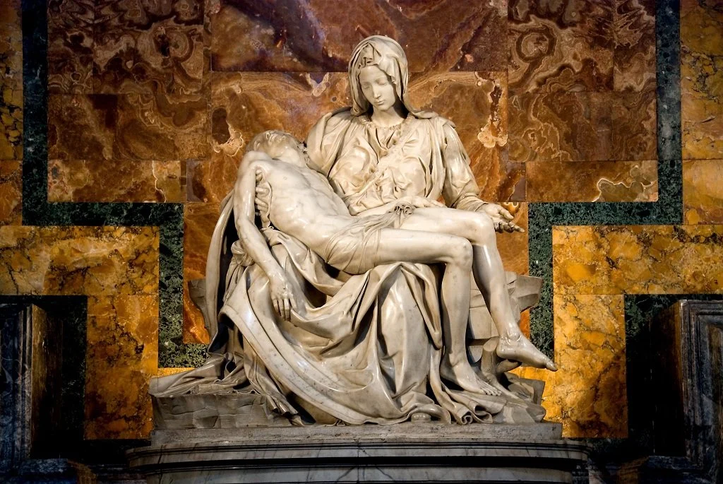 The marble sculpture of the Pieta showing Mary holding the body of Jesus after the crucifixion, with a detailed marble background.