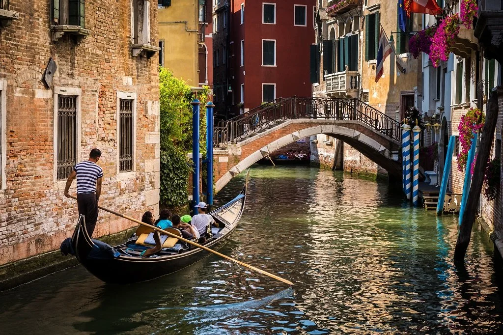 Gondola ride on a canal in Venice, Italy with a gondolier guiding the boat past historic brick buildings