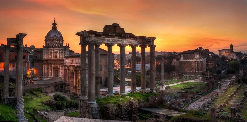 Ancient ruins of Roman temples and buildings at sunset in Rome, Italy.