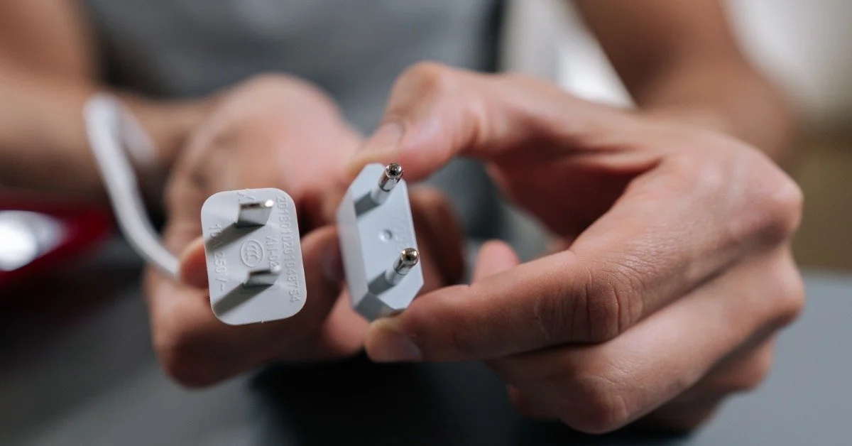A close-up of someone holding a Type A plug and a Type C plug next to each other for comparison.