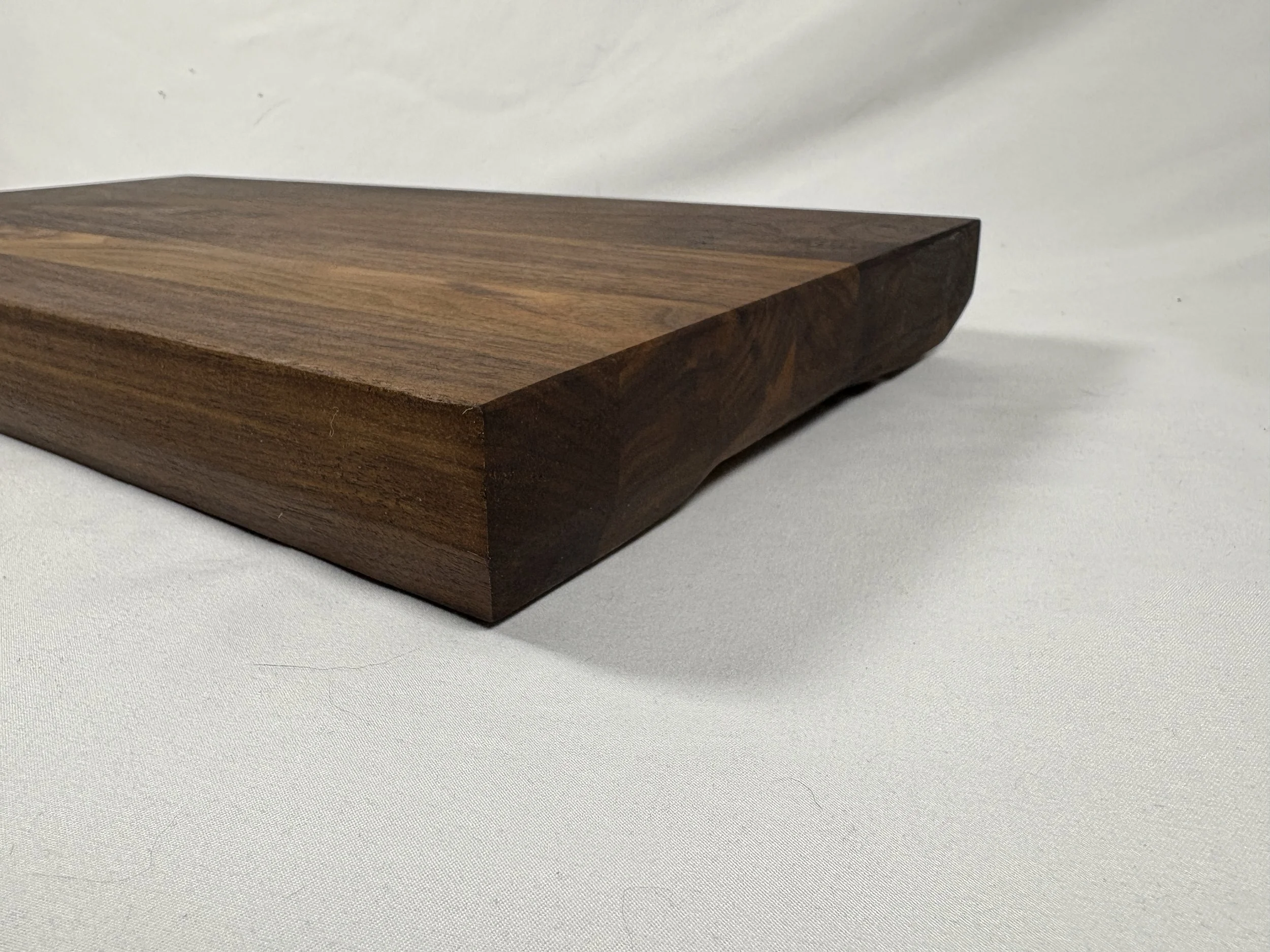 12" x 18" walnut cutting board. 22 degree chamfer along the bottom, and 45 degree chamfer in the centre as handle.
