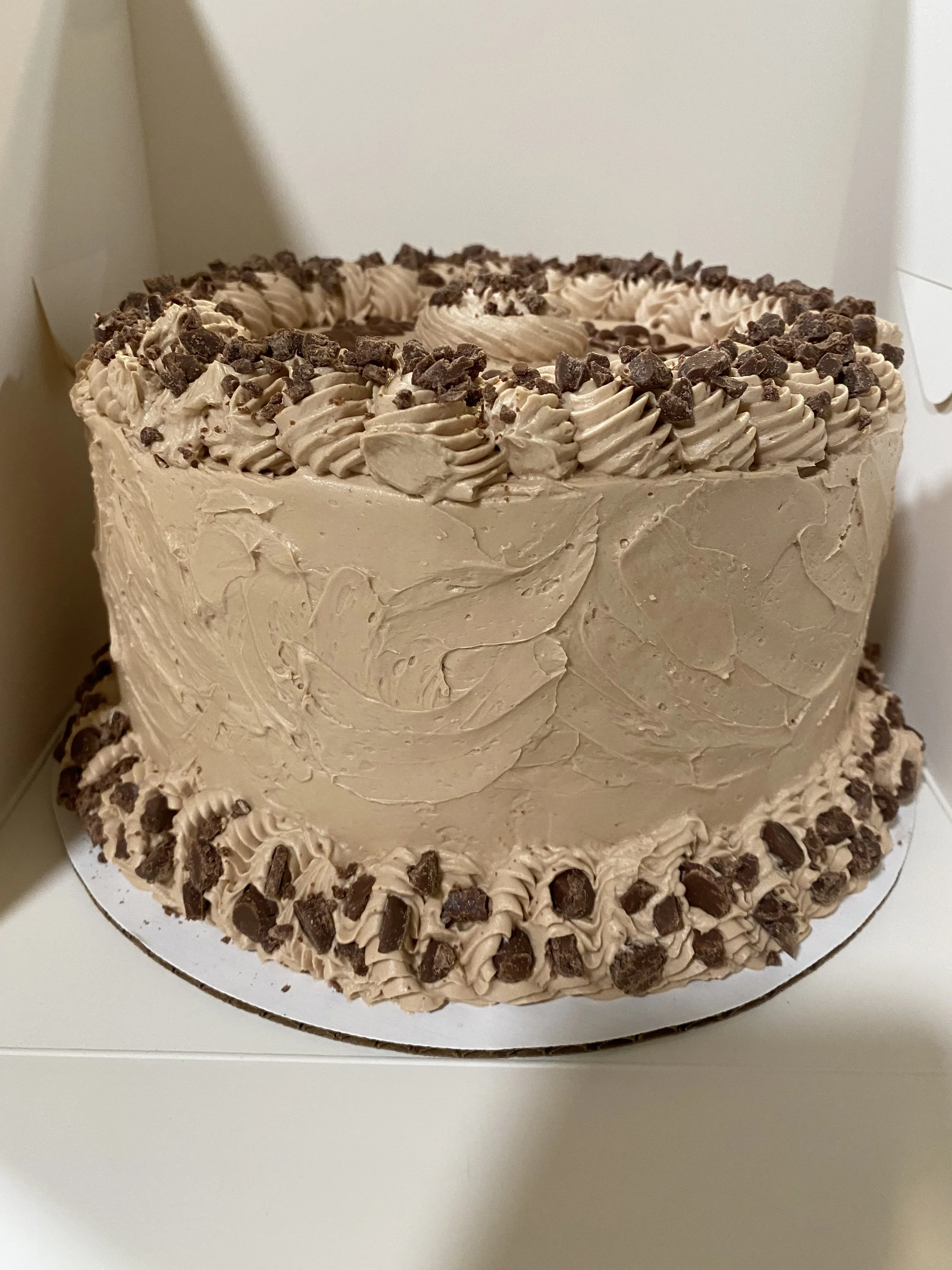 Milk Chocolate Cake. Cake layers filled with Milk Chocolate Italian Meringue Buttercream.  Frosting Milk Chocolate Italian Buttercream.  Garnished with Milk Chocolate pieces and Frosting Swirls.   

6" round cake.  3 layers.