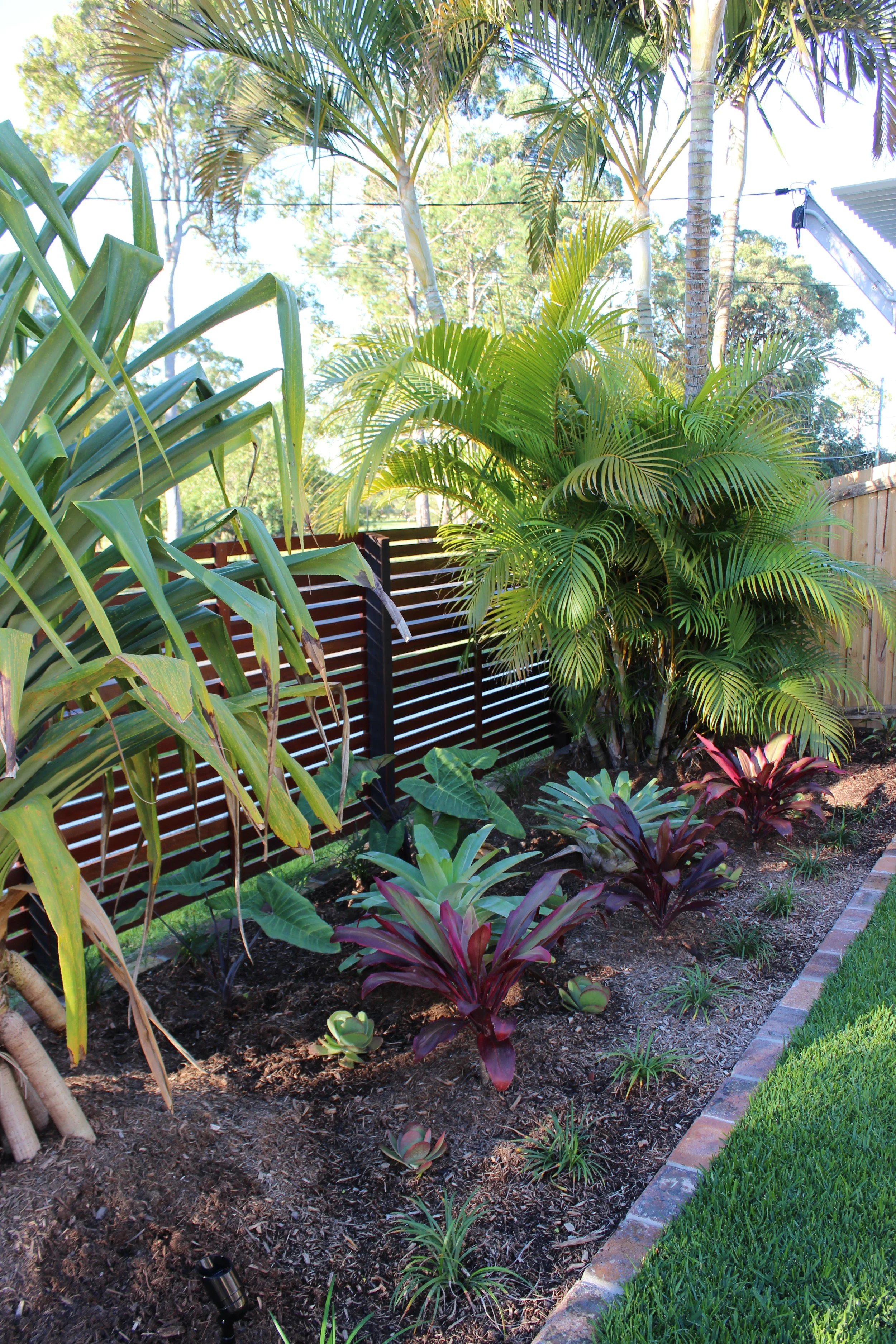 Modern backyard with a swimming pool, outdoor seating area with wooden posts, and a covered pavilion at dusk.