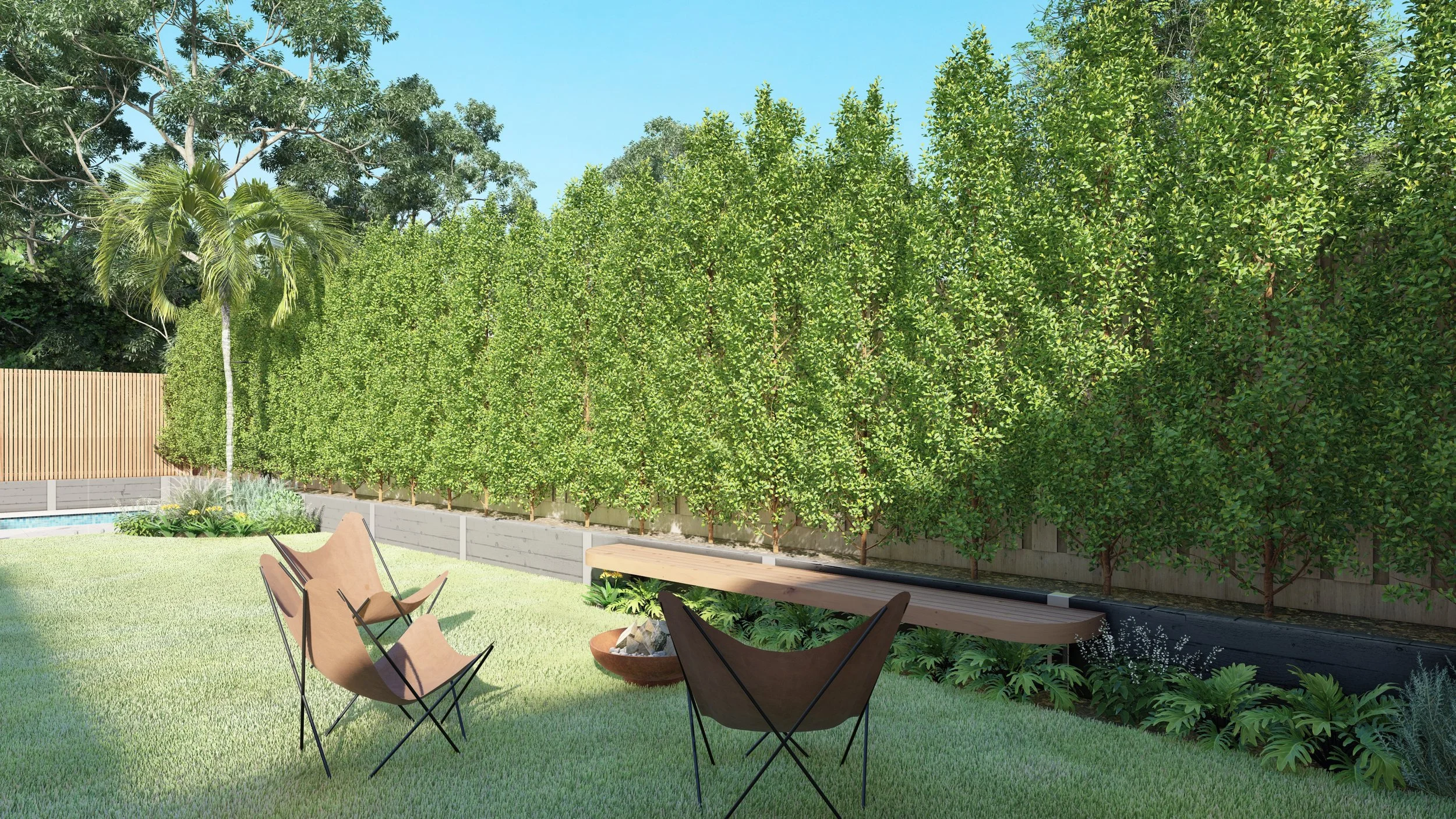 A backyard with green grass, a wooden fence, and a variety of trees including palm and deciduous trees. There are outdoor chairs and a bench, with a small garden bed along the fence.