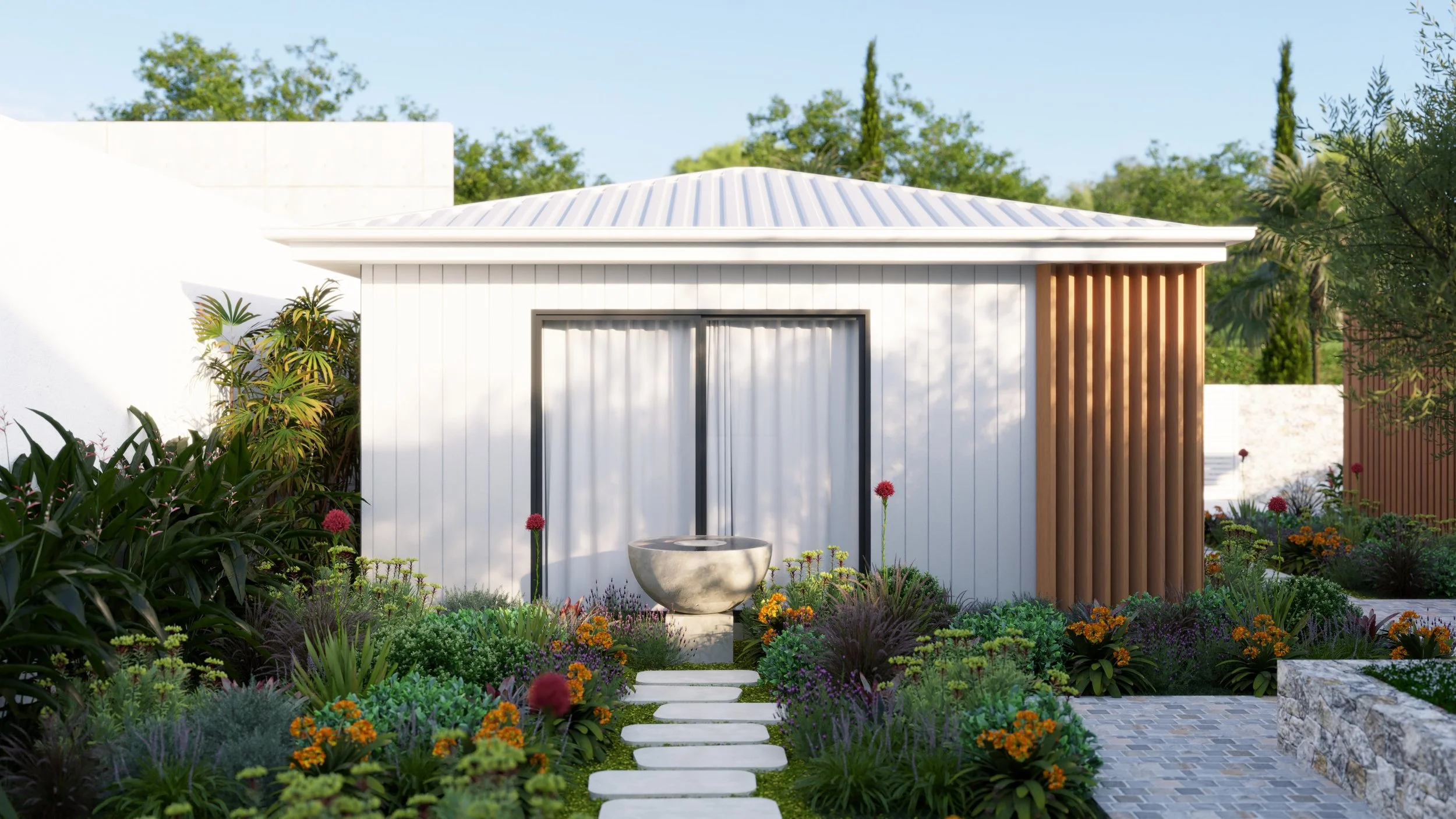 Modern small white house with a metal roof, surrounded by colorful garden with flowers and greenery, stone pathway leading to sliding glass door, and a stone fountain in front.