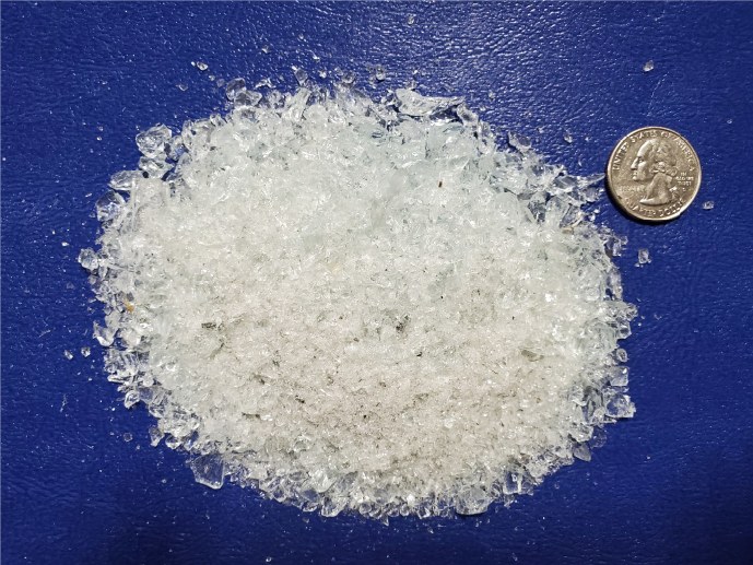 Granulated white crystalline substance on blue surface with a quarter coin for size reference.