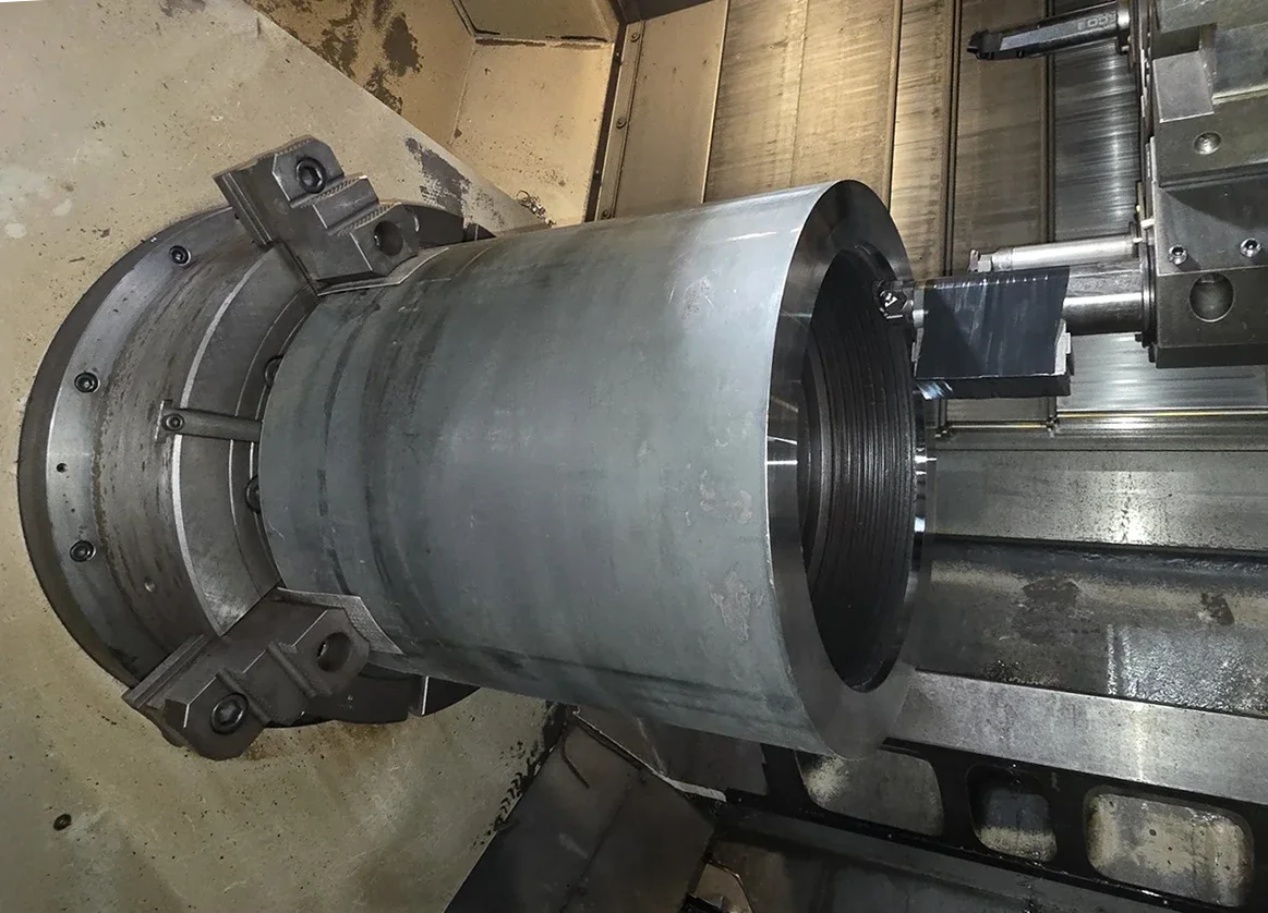 Close-up of a metal cylindrical component secured on a CNC machine during manufacturing.