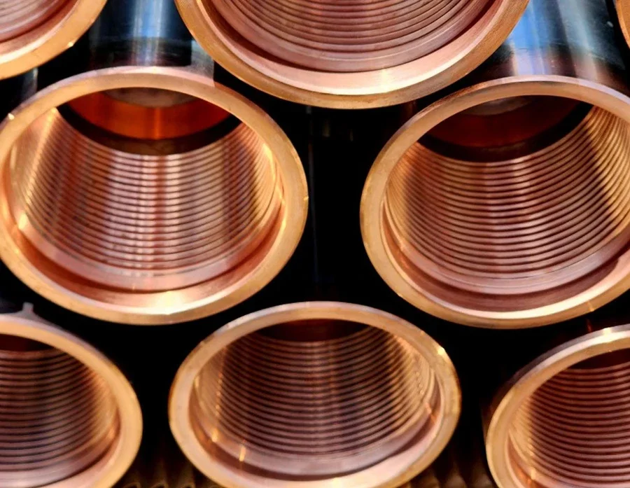 Close-up of several copper pipes stacked together, showing the inside with concentric grooves.