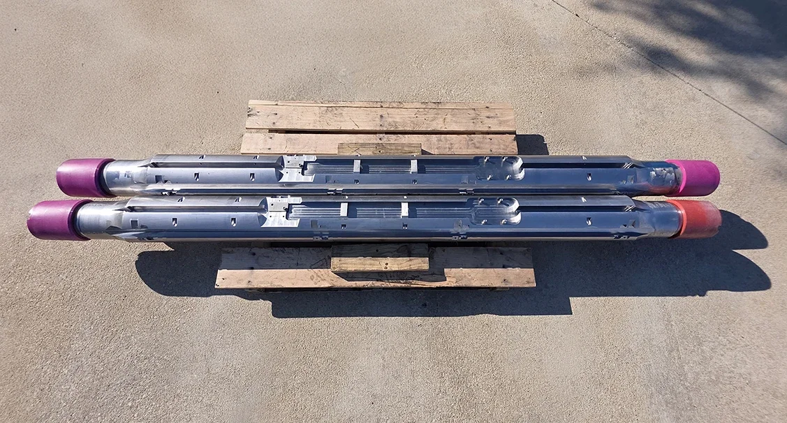 Customized guage mandrels designed by PetroQuip Energy Services for an international customer sitting on a pallet on a concrete floor.