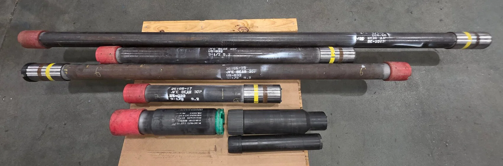 Customized guage mandrels designed by PetroQuip Energy Services for an international customer sitting on a pallet on a concrete floor.