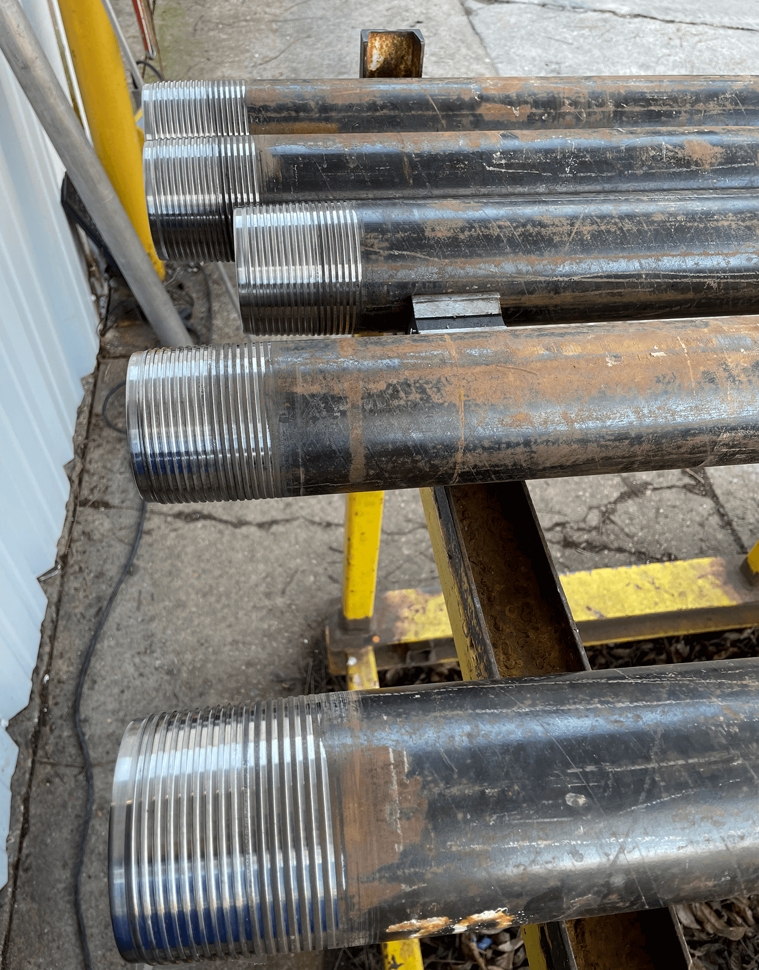 A series of custom threaded pipes showing threading solutions by PetroQuip Energy Services.