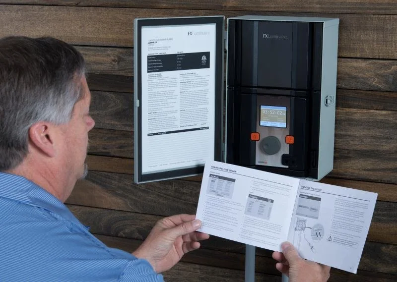 Technician inspecting and repairing outdoor landscape lighting transformer power center in Rogers Arkansas