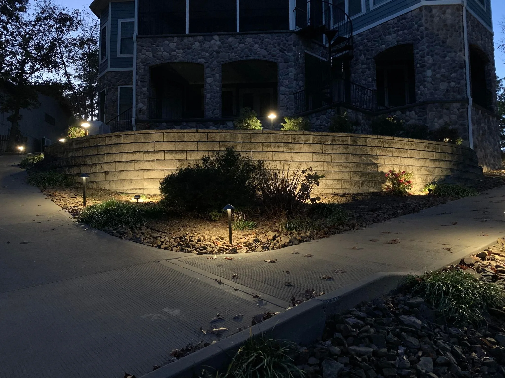 Landscape retaining wall with path lights and uplighting at night in Centerton Arkansas by Premier Outdoor Lighting