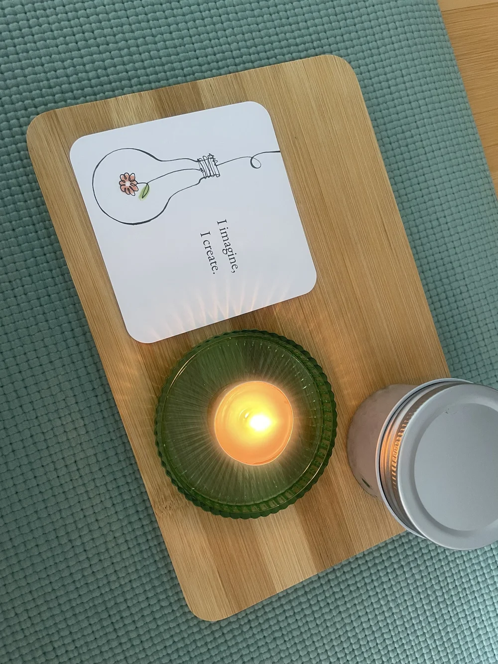 A candle and reflection card on a green mat