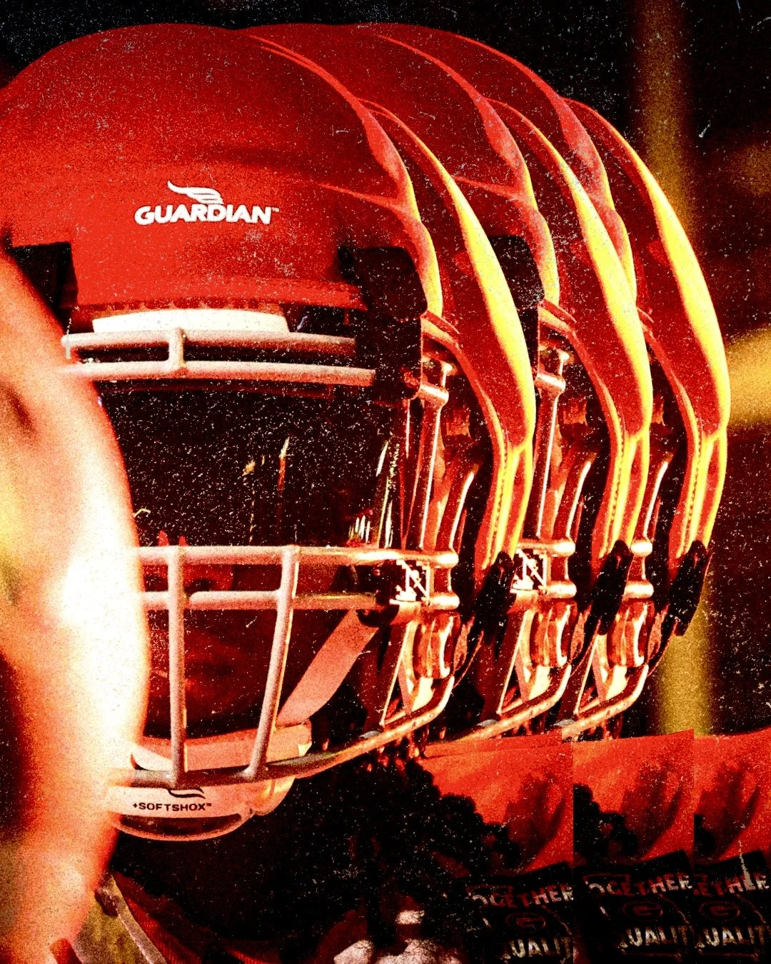 Line of American football helmets in red with a white Guardian logo on the side.