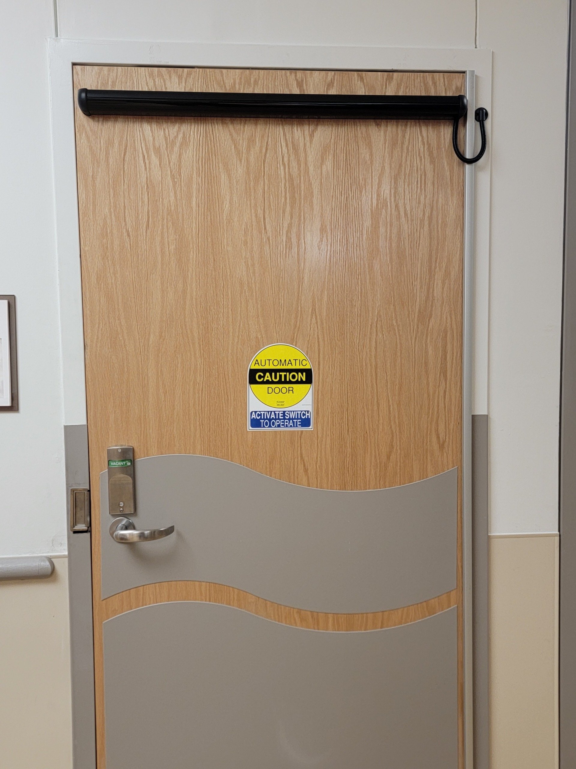 Wooden door with automatic caution sign and gray wave design