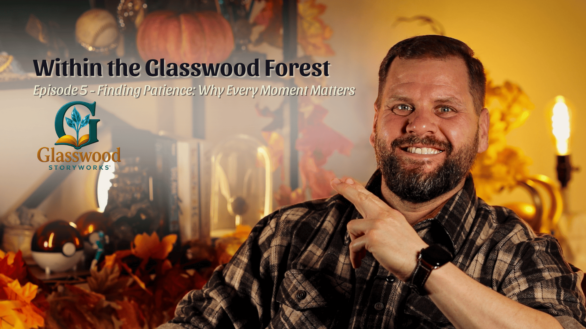 A man smiling and pointing at a logo in a cozy, autumn-themed room with pumpkins, leaves, and warm lighting.