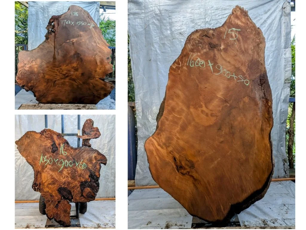 Three large wooden slabs with handwritten measurements in yards on each slab, displayed outdoors against a backdrop of trees and a tarp.