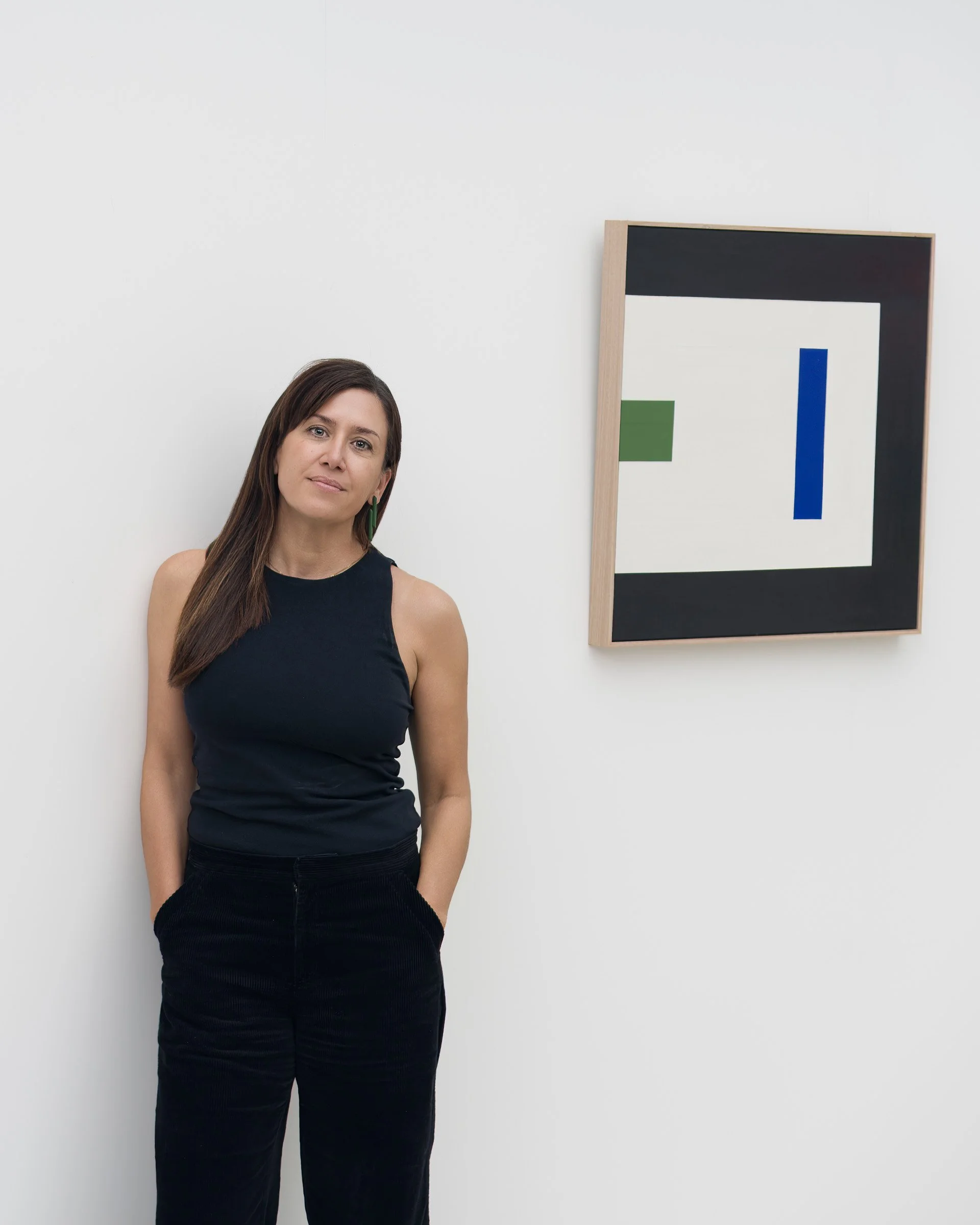 Artist standing next to abstract artwork in gallery