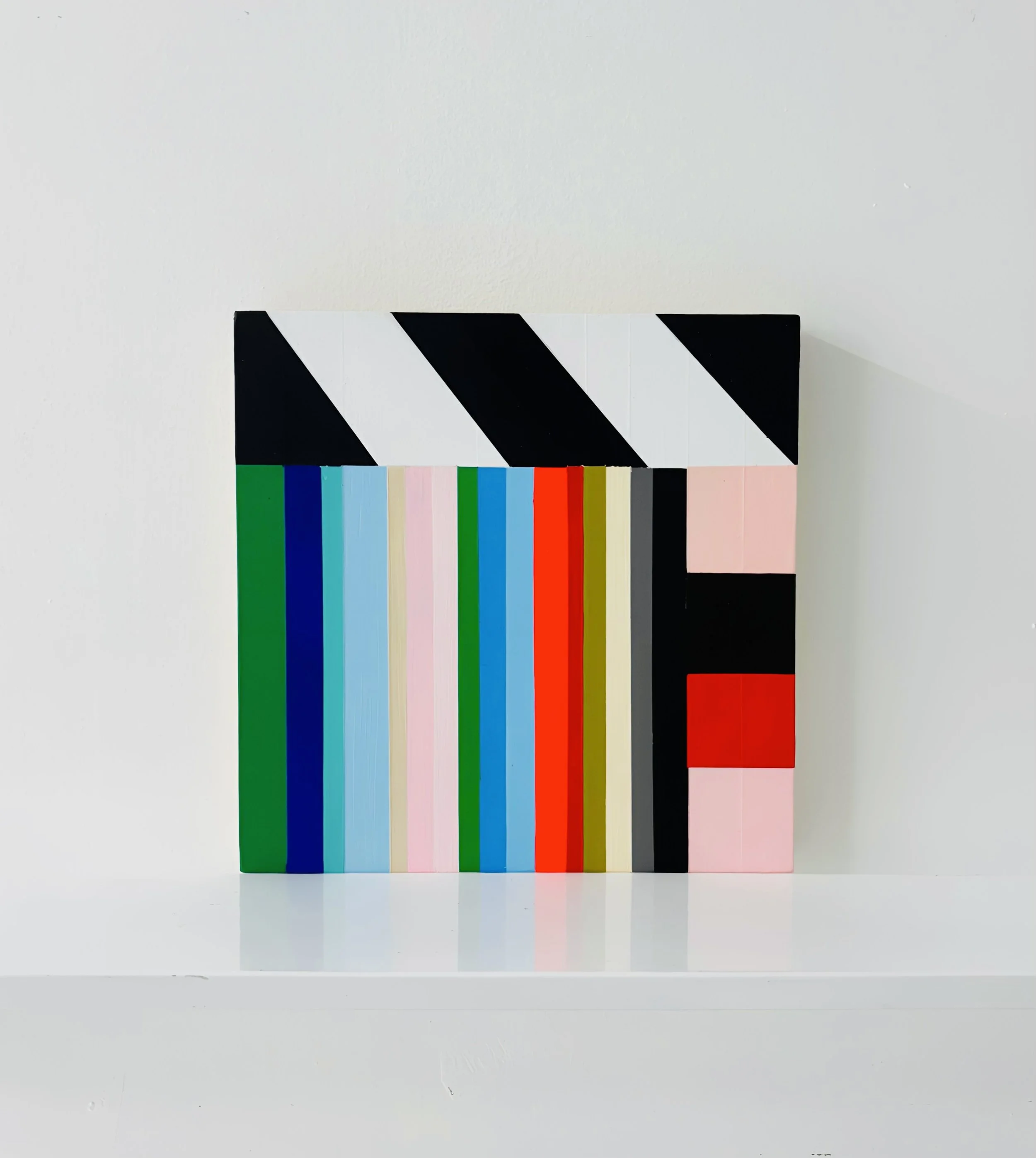 A colorful abstract painting with vertical and diagonal stripes in green, blue, pink, red, black, white, and beige on a rectangular canvas mounted on a white wall. modern art . small scale abstract art.