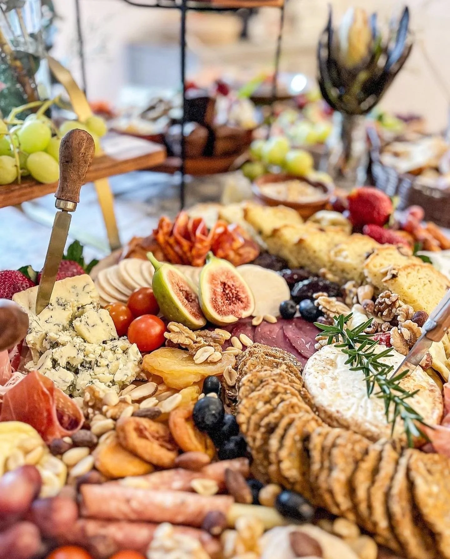 Charcuterie board with assorted cheeses, cured meats, figs, grapes, nuts, crackers, and garnishes.