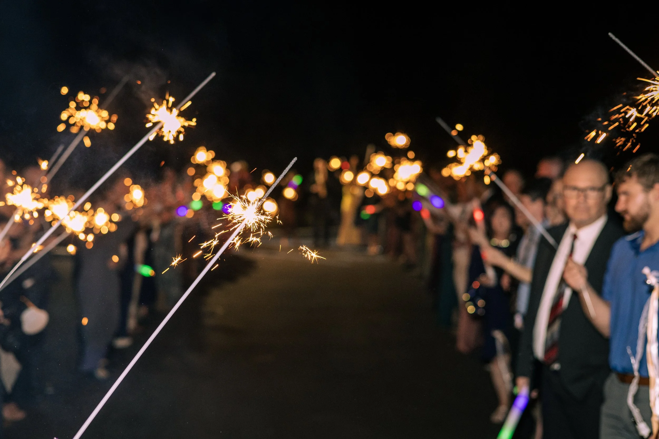 People holding sparklers in the dark, celebrating at night.