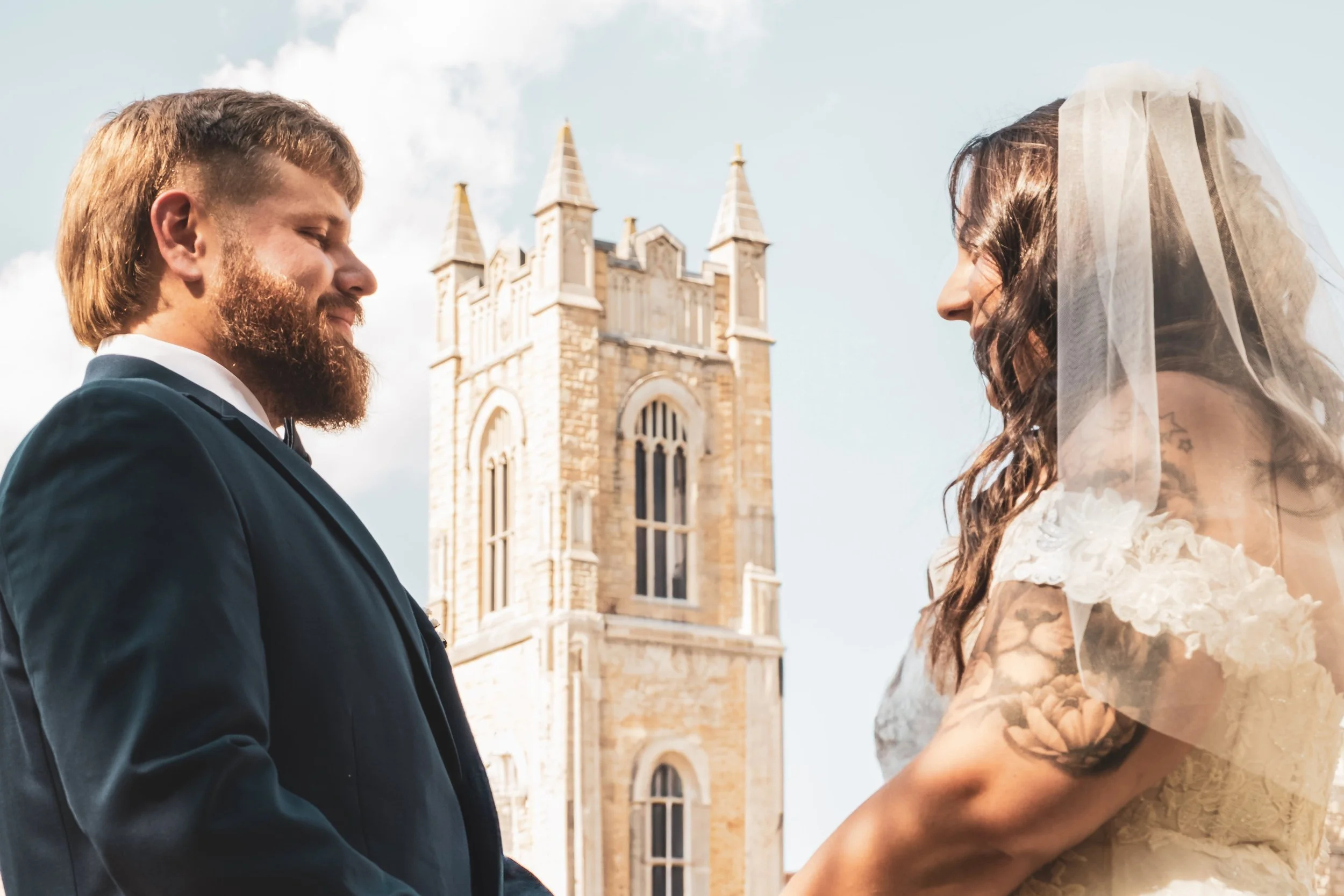 A bride and groom standing outside a church, gazing into each other's eyes during their wedding ceremony.