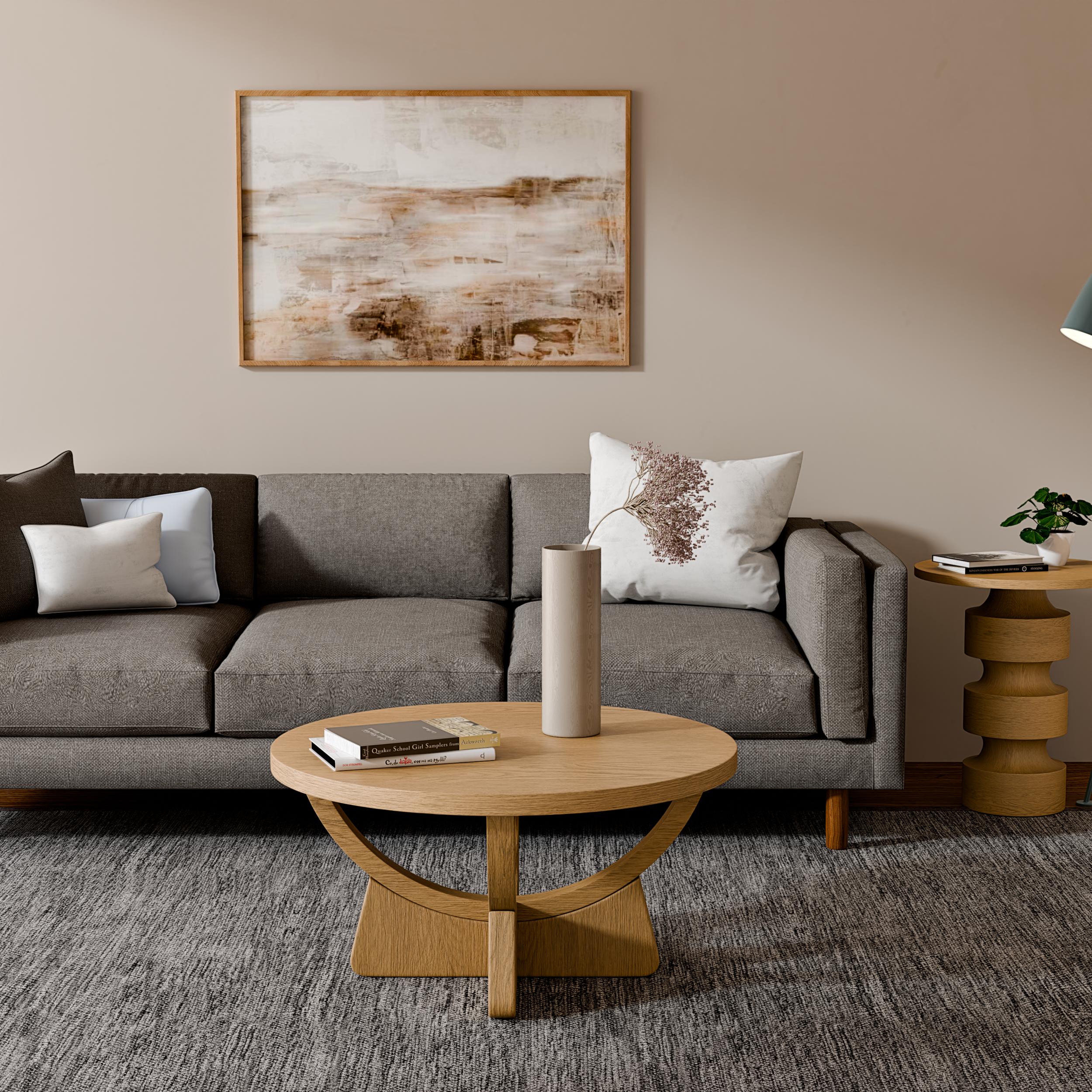 Modern living room with a gray sofa, abstract wall art, wooden coffee table with vase, side table with books and plant, and a gray rug.