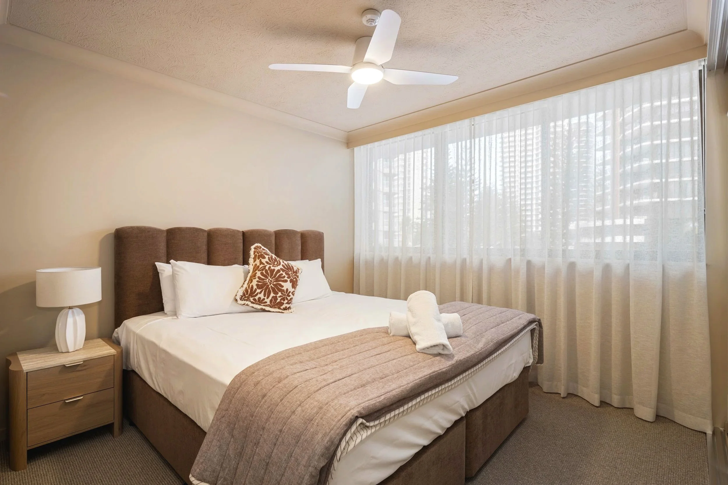 Warm, colour drenched Bedroom using earthy beiges and browns, soft sheers and textural carpet. 