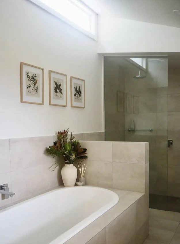 Bright, sun drenched Bathroom with raked ceiling, timber window, neutral tiles to Bath and Shower. 