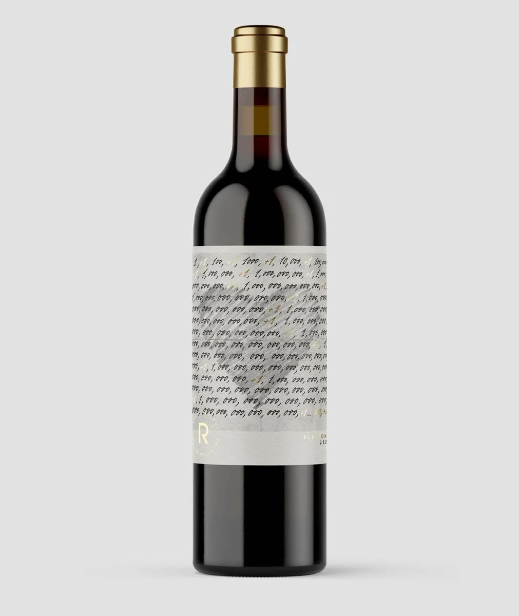 A bottle of red wine with a gold foil top and a white label with handwritten-style text.