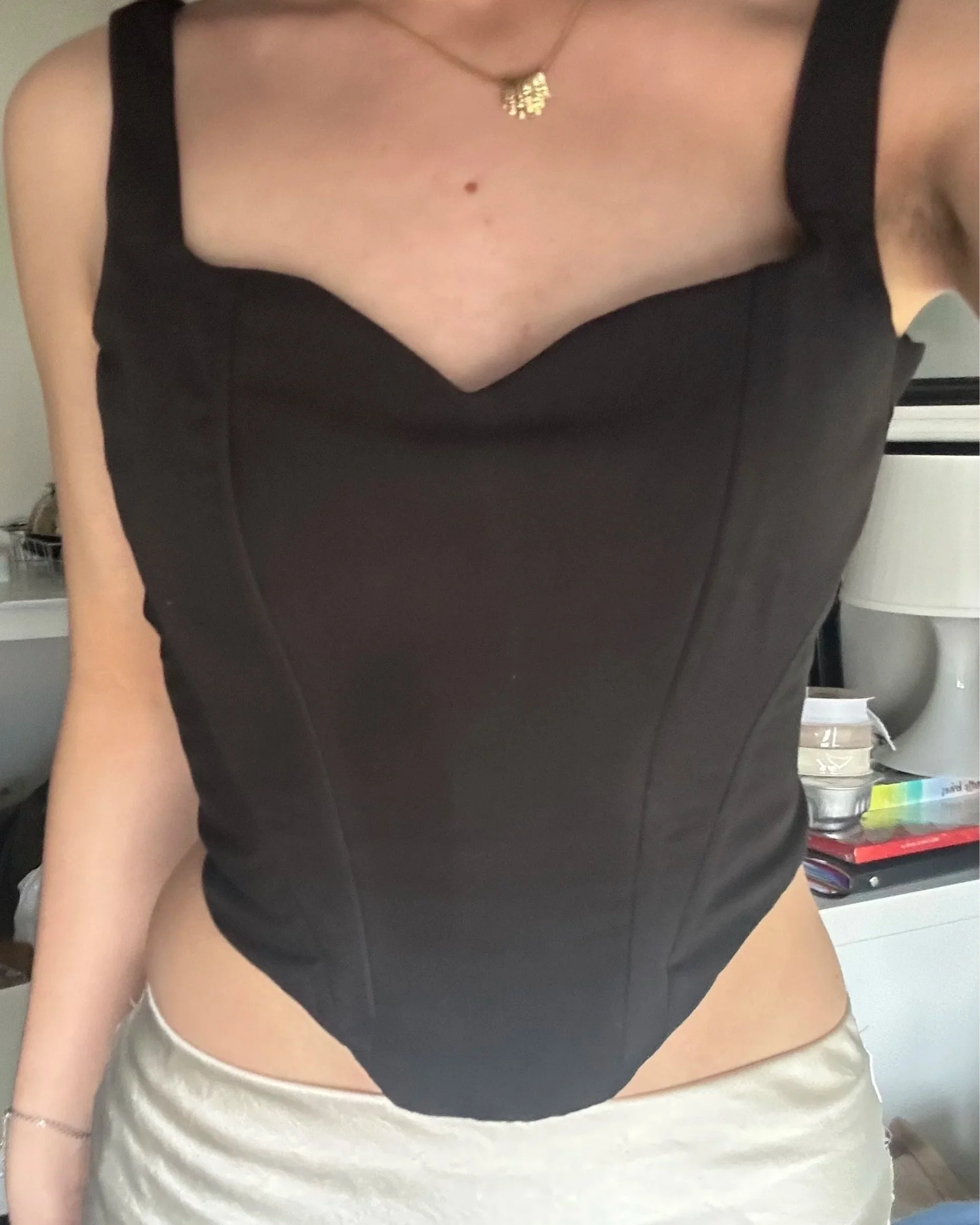 Personne portant un haut noir sans manches et une jupe claire.