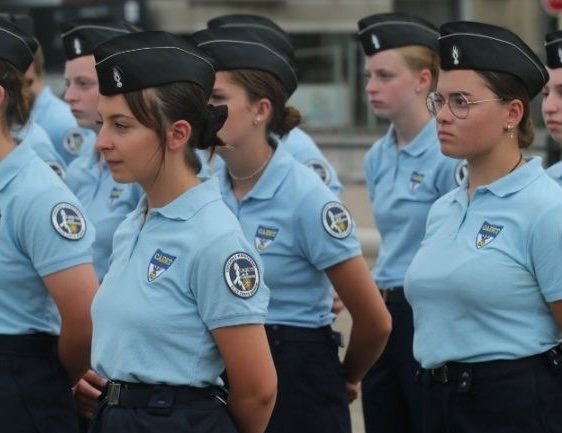 Groupe de personnes en uniforme bleu et casquettes noires lors d'une cérémonie.