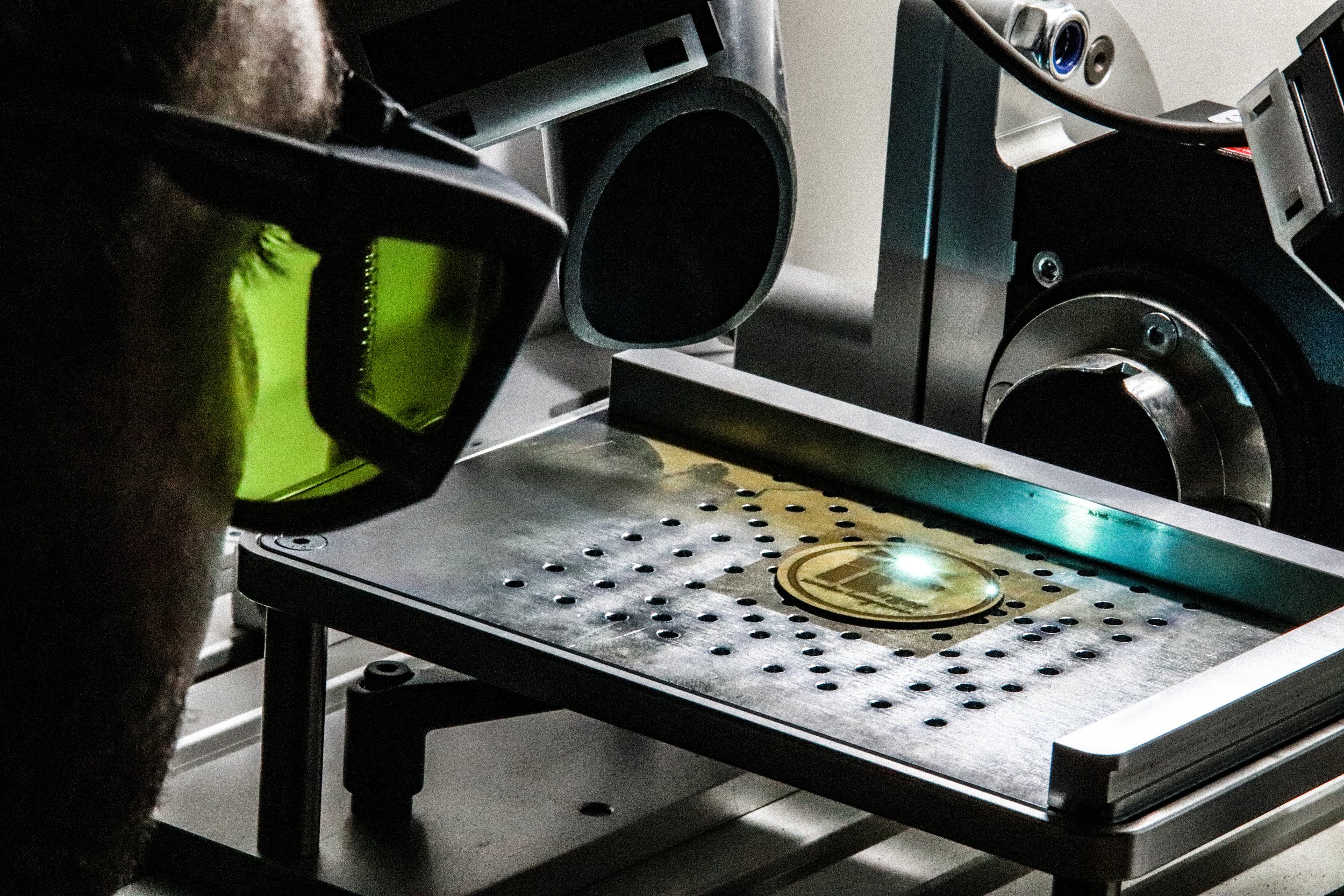 Bram Burger bedient zijn lasergraveermachine die een metalen object aan het graveren is.