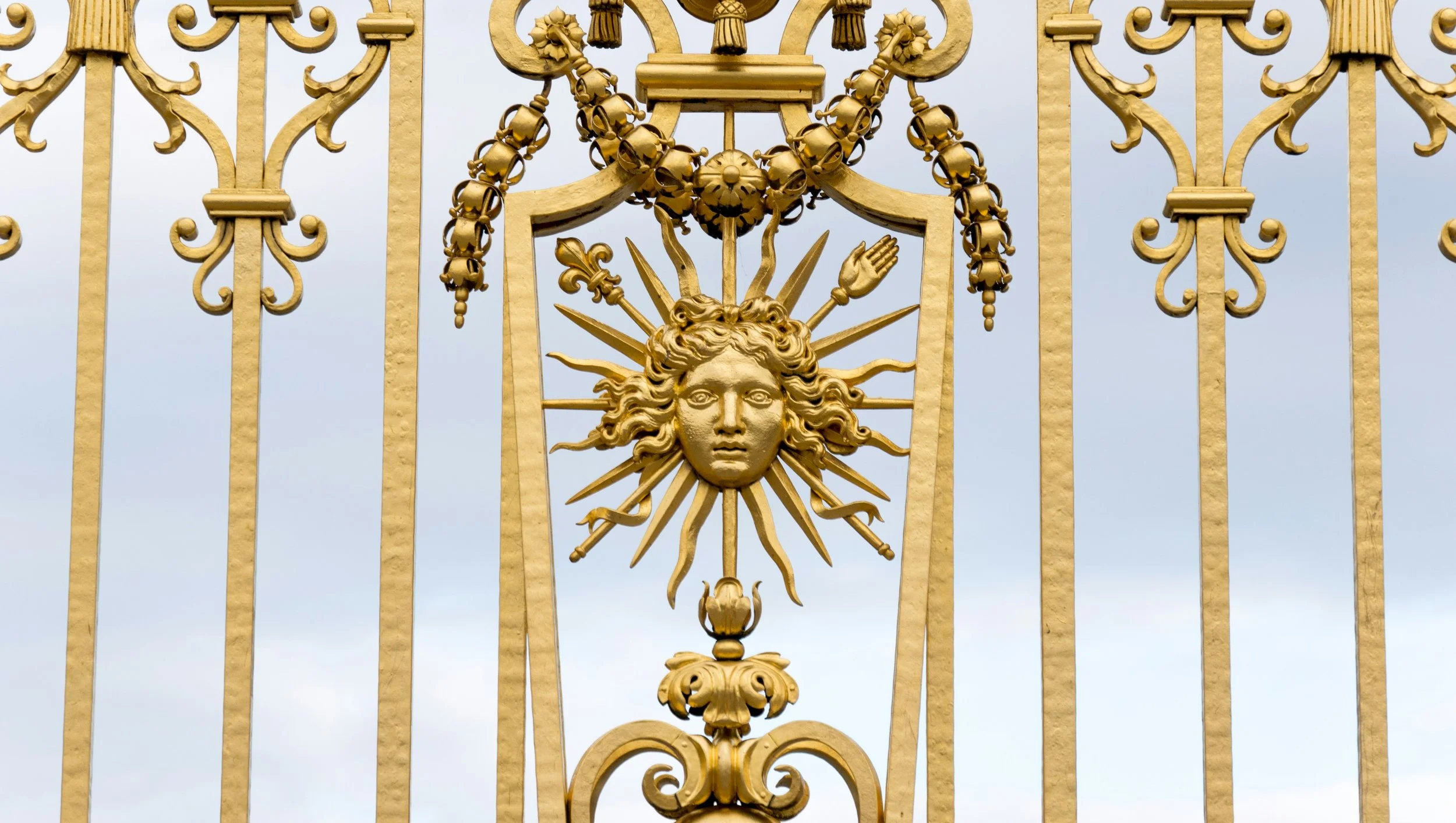 Close-up of ornate golden gate with sun design
