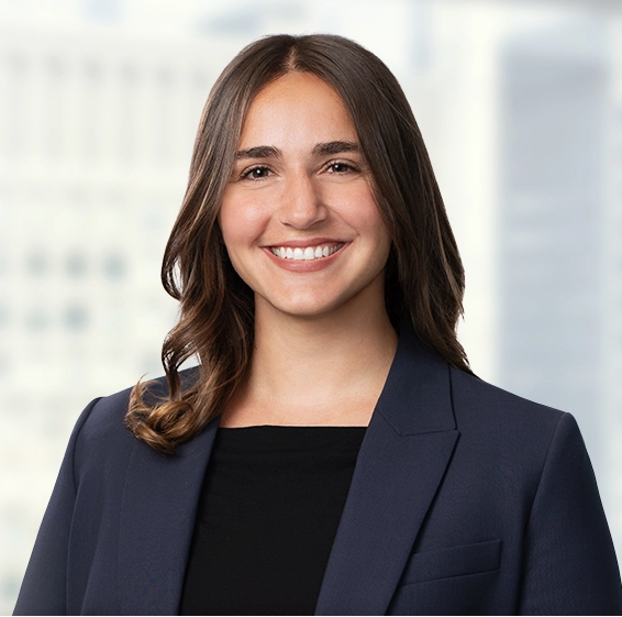Portrait of a woman smiling in professional attire with a black blazer and white top against a plain white background.