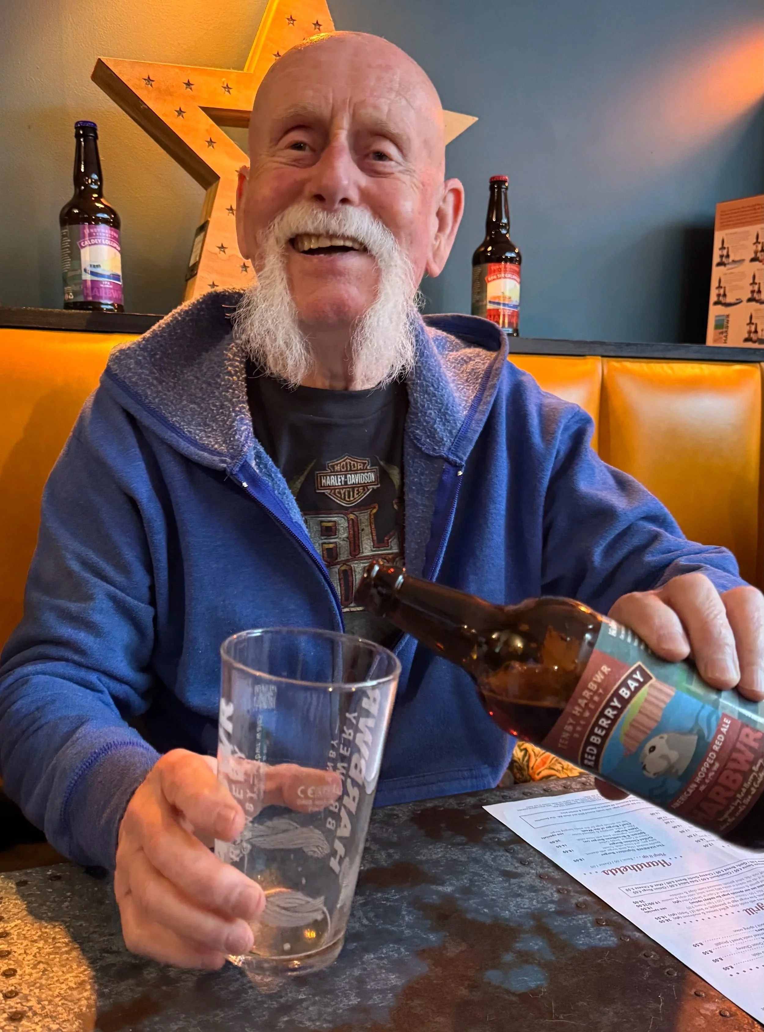 a holiday maker smiling and pouring a beer into a glass 