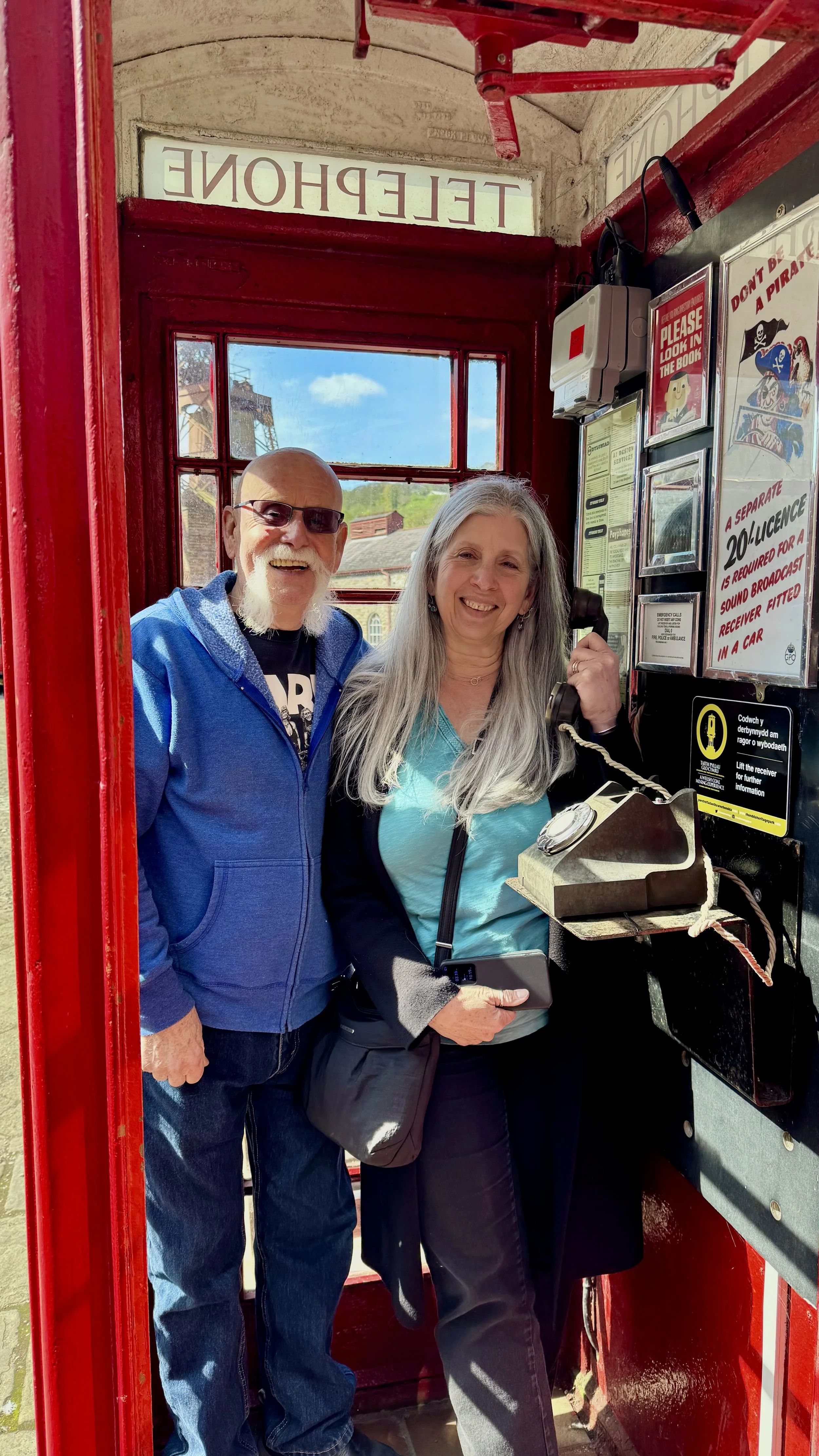  a holiday maker couple posing in a red telephone box 