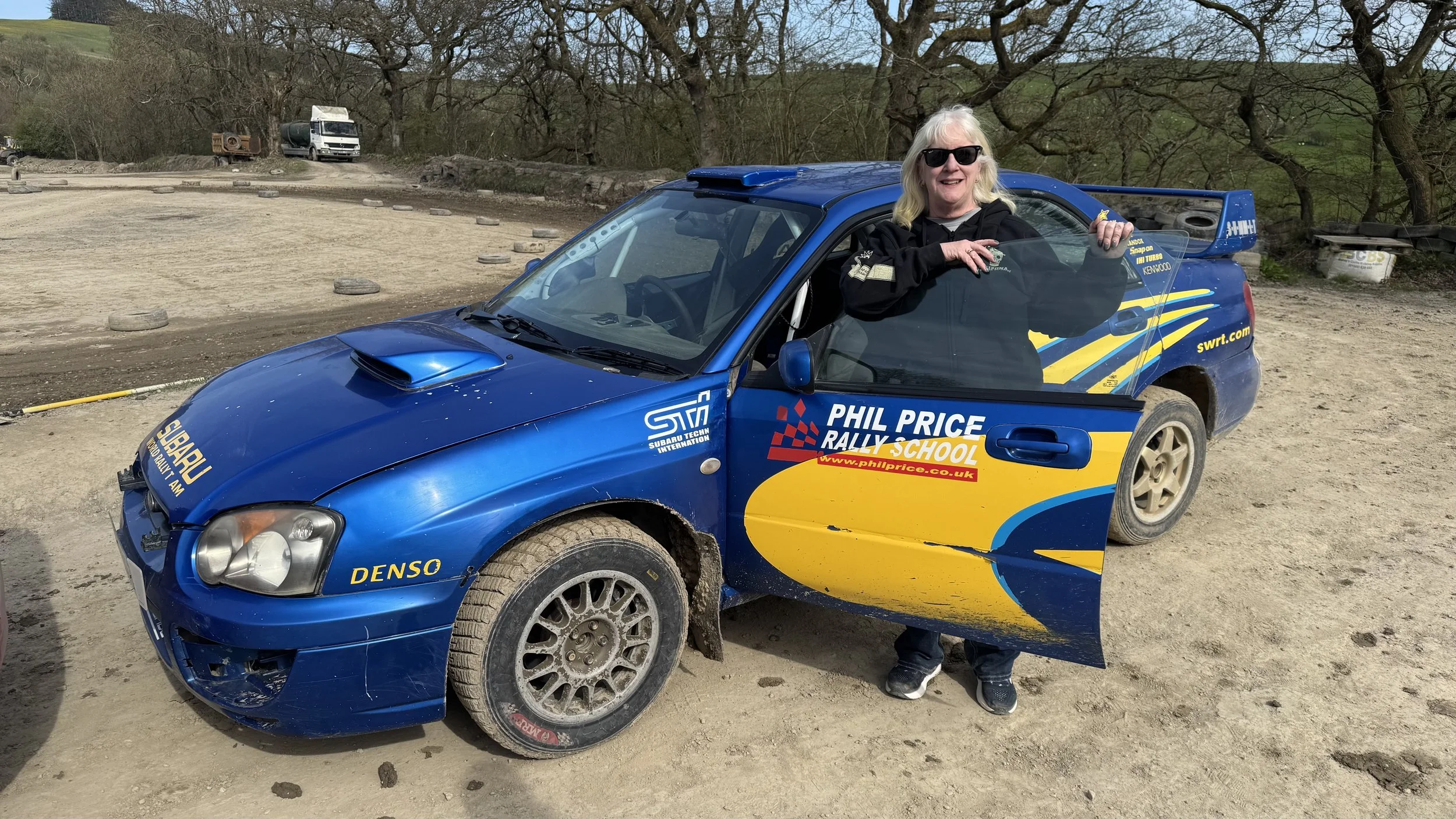  a person standing next to a subaru rally car 