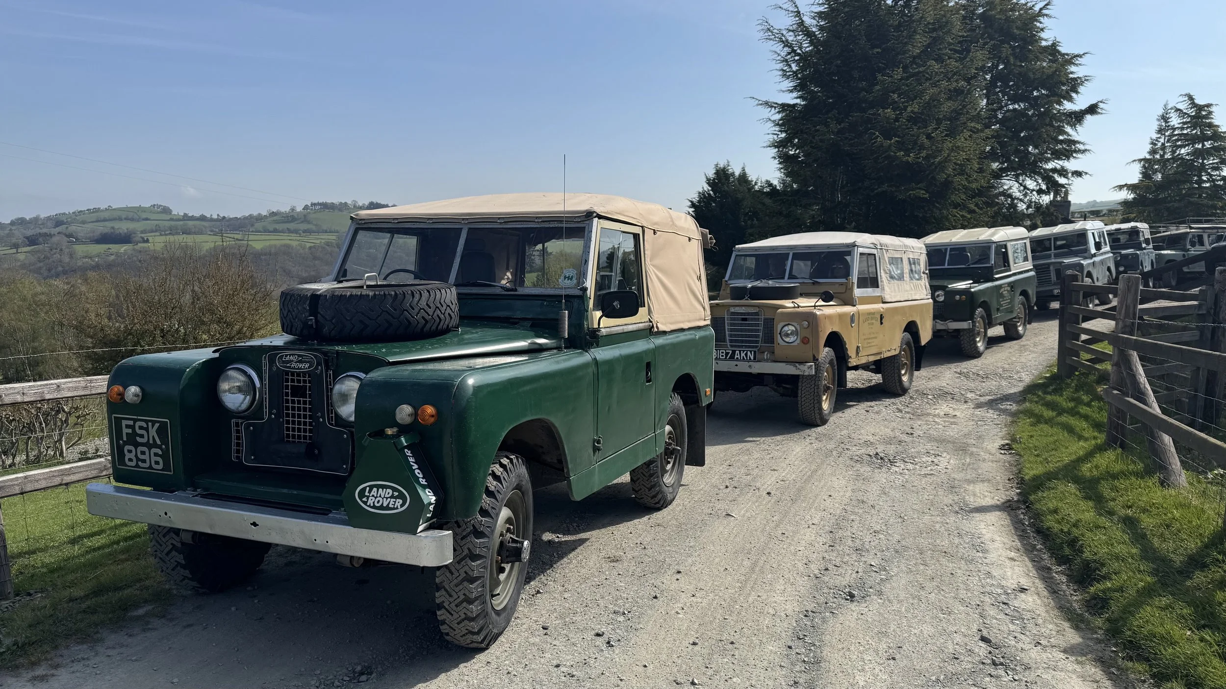  a row of classic land rovers in the countryside 