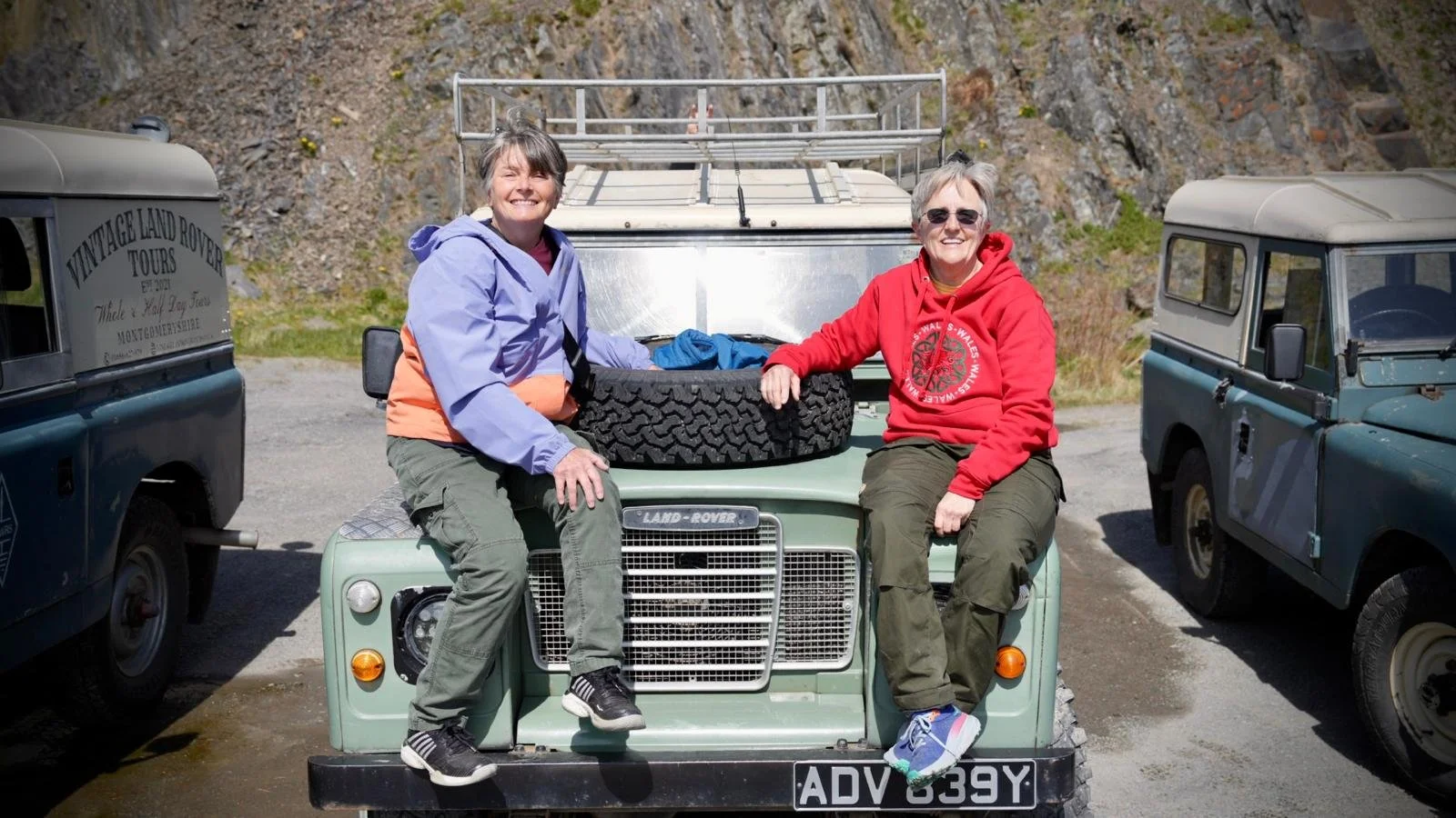  holiday makers sitting on the bonnet of a classic land rover 