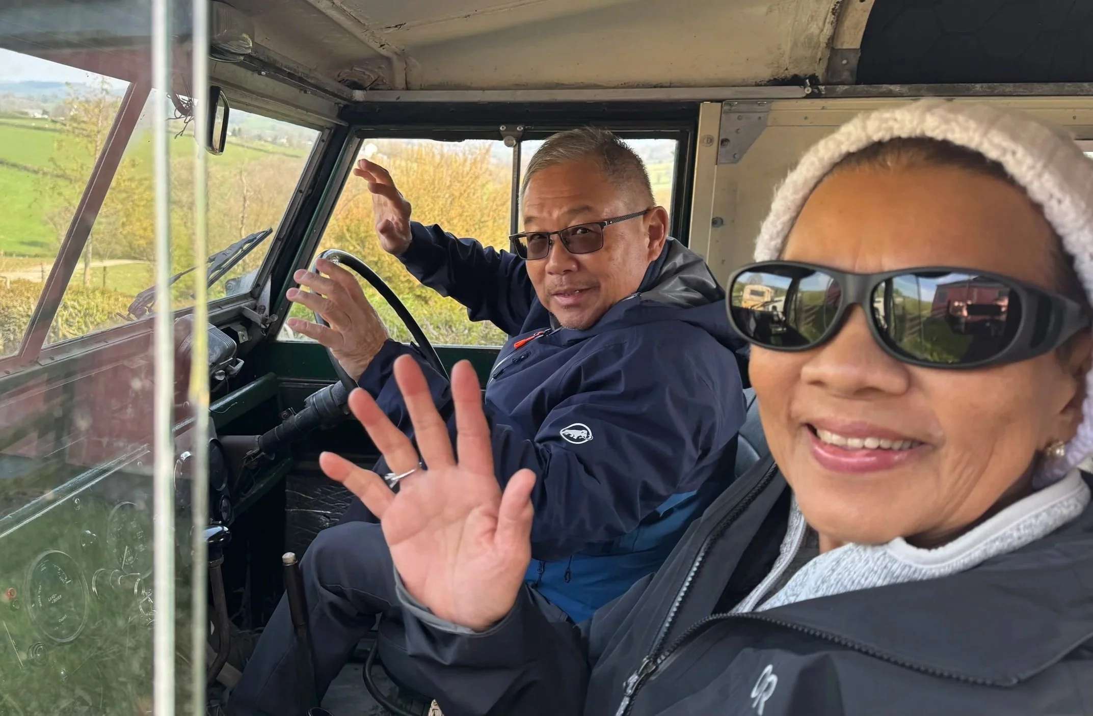  holiday makers waving from a vintage land rover 