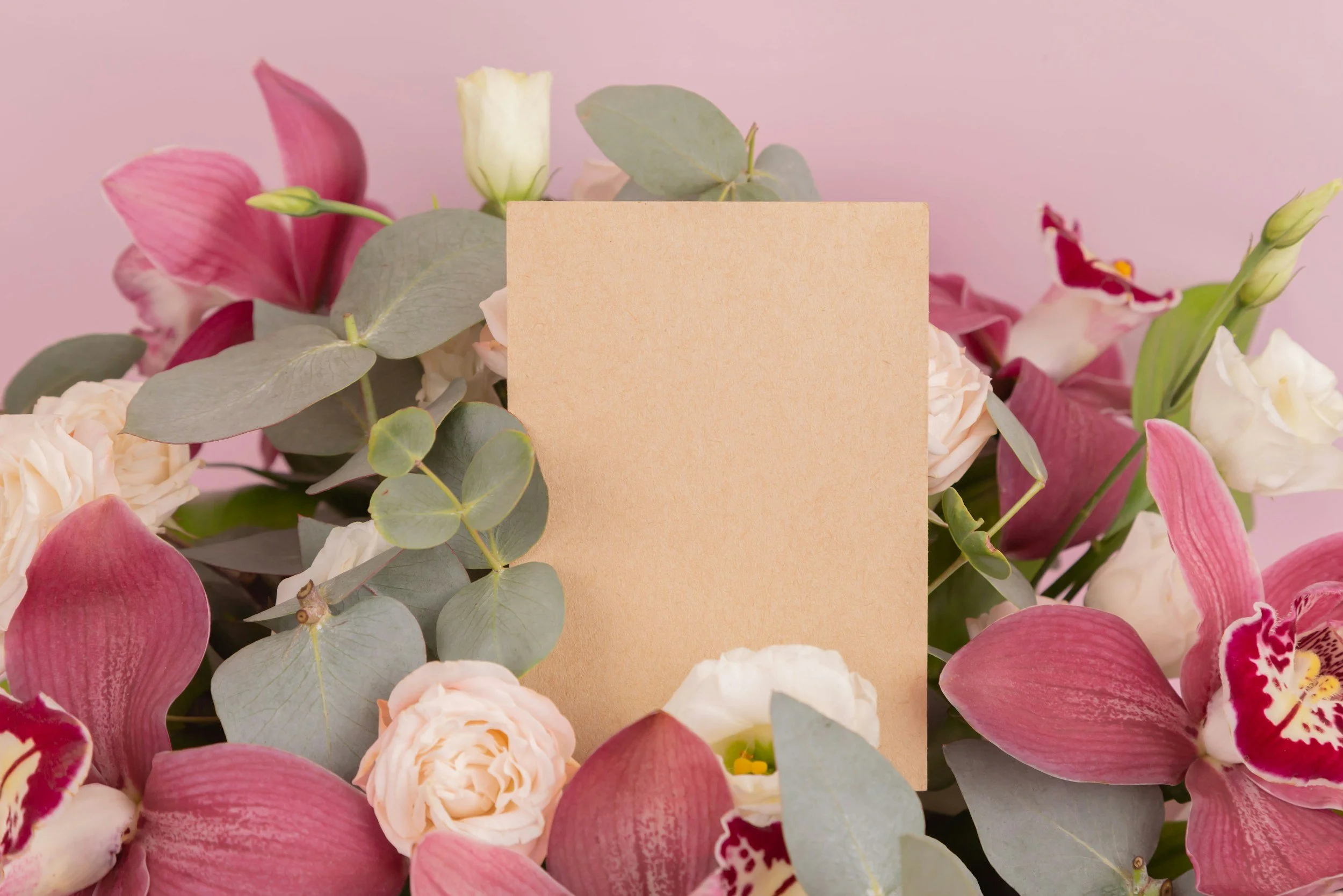 Fiore di orchidea e altri fiori rosa e bianchi con foglie di eucalipto e carta crema