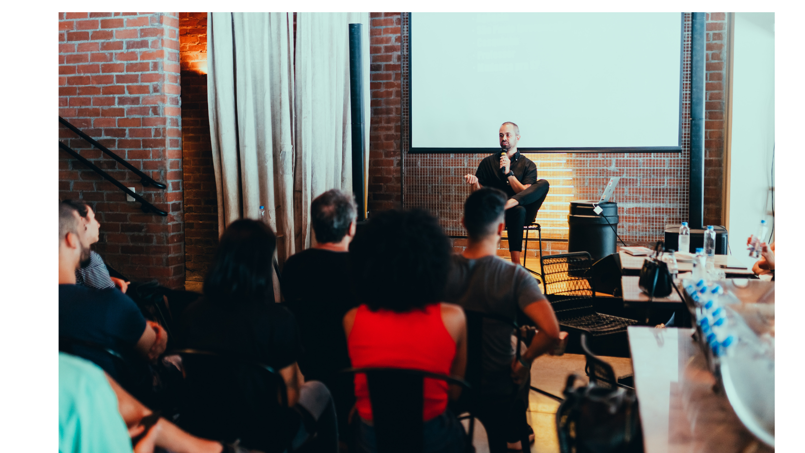 プレゼンターがスライドを使って聴衆に話している会議またはワークショップの様子。